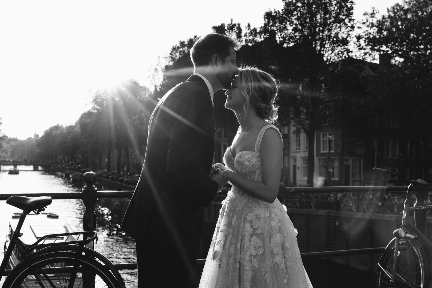 Silhouetted wedding couple against bright sunlight outdoors.