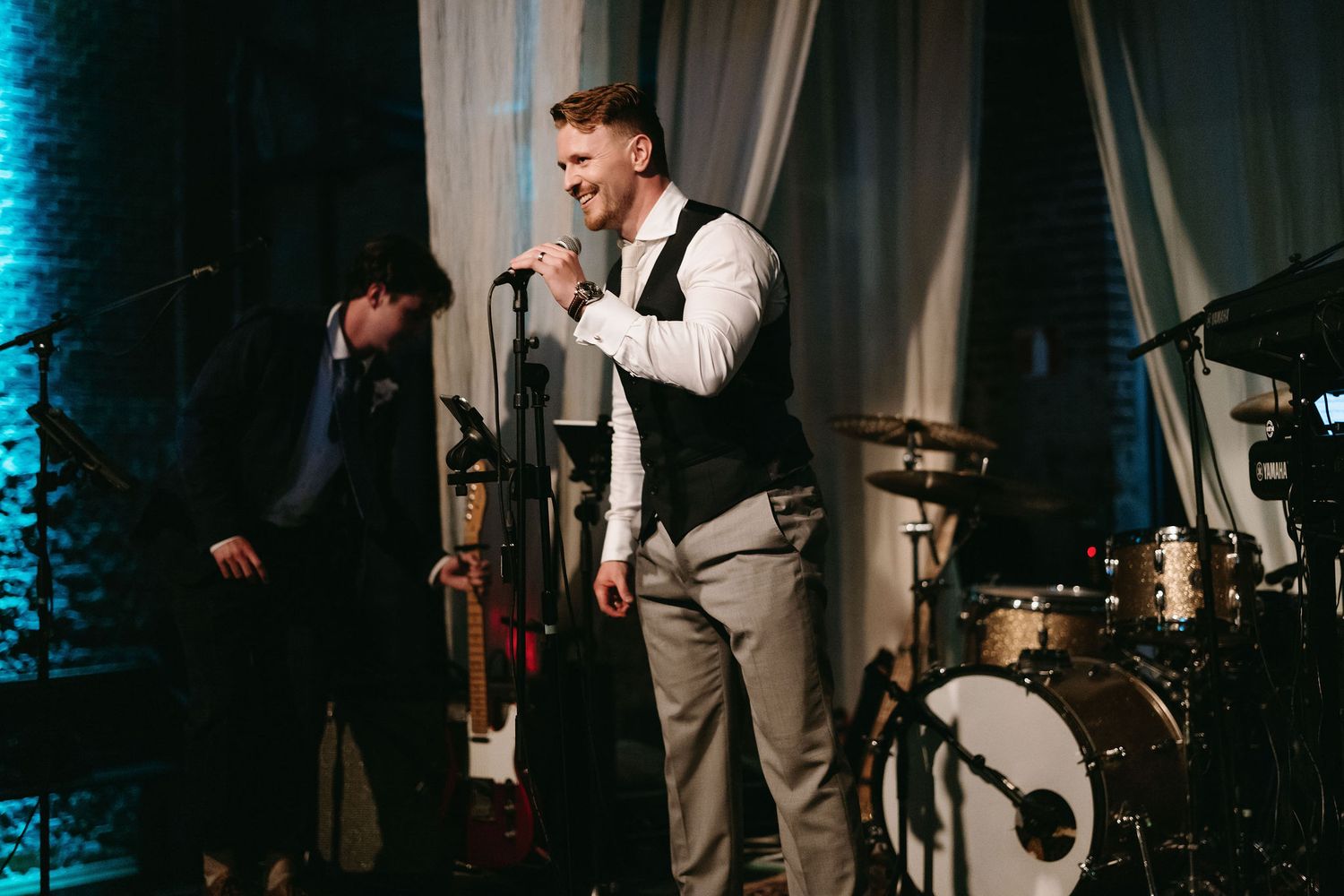 Live band performs on stage with blue lighting at wedding reception.