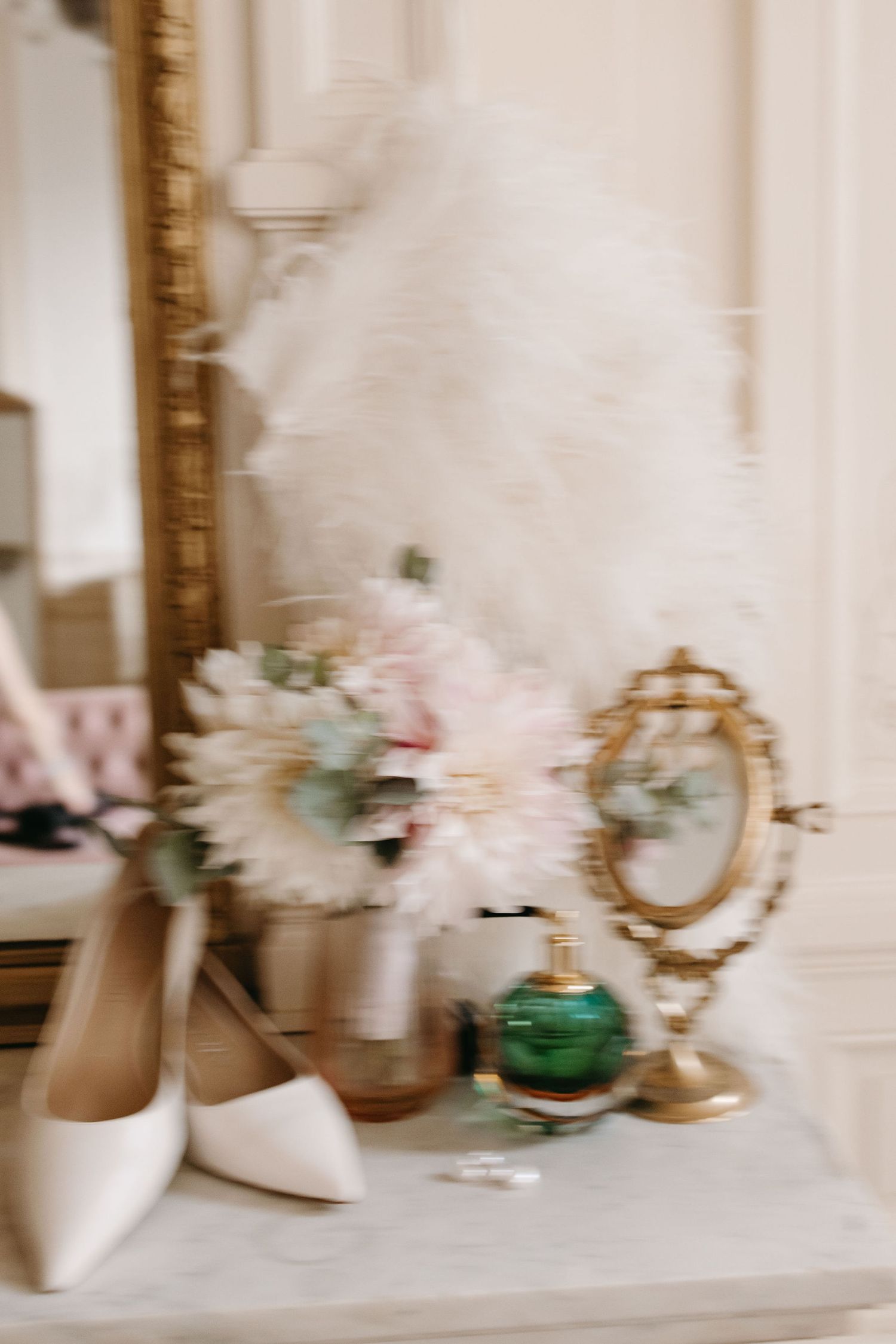Wedding details with white shoes, vintage mirror, and soft floral arrangements on display.