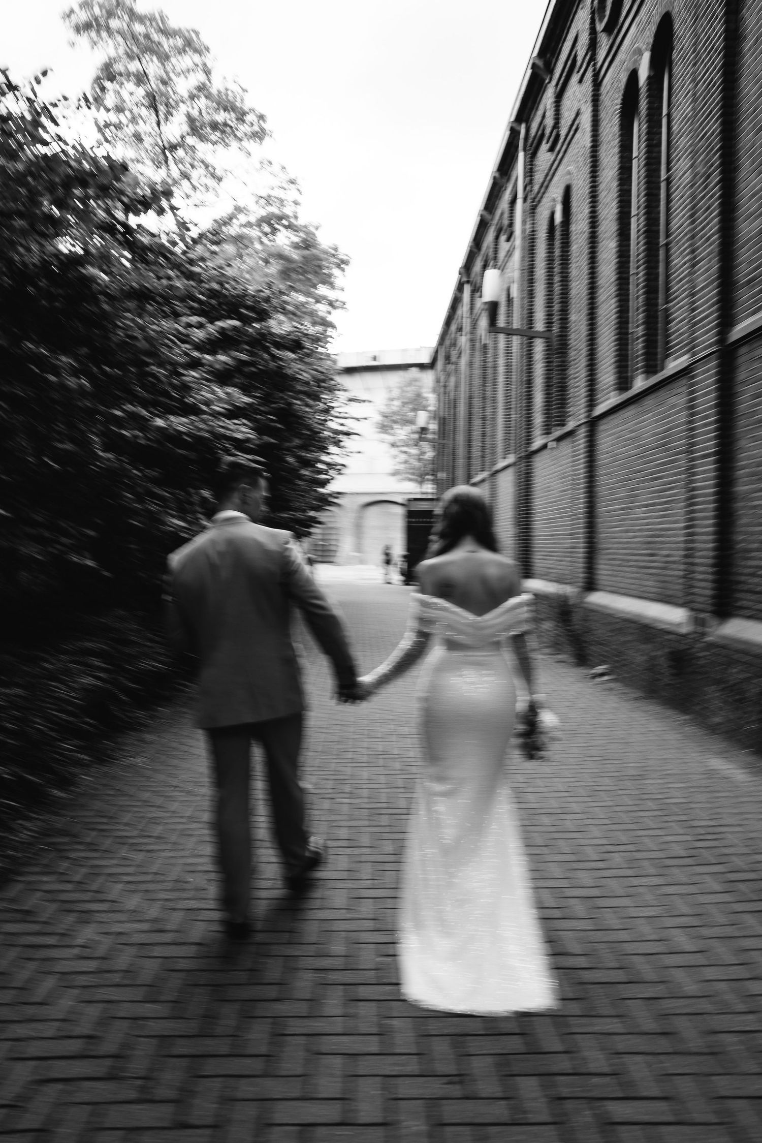 Artistic black and white photo of couple walking down a brick pathway.