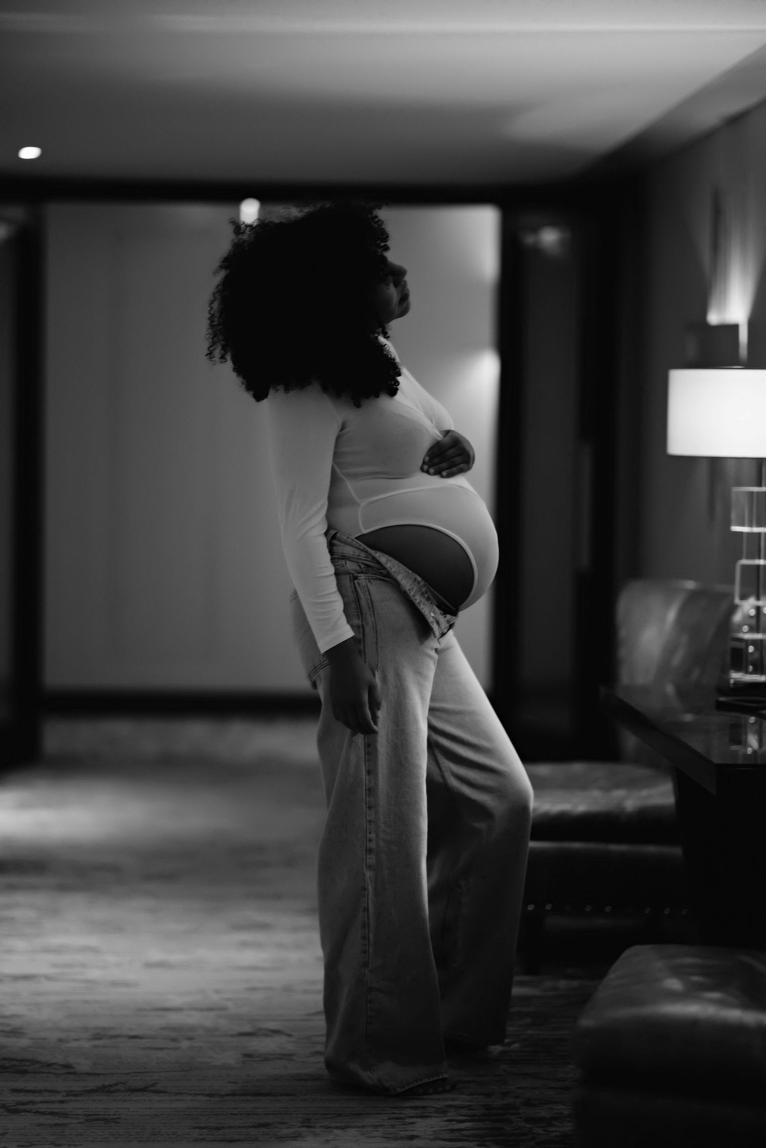 Black and white maternity portrait in an elegant hotel room setting.
