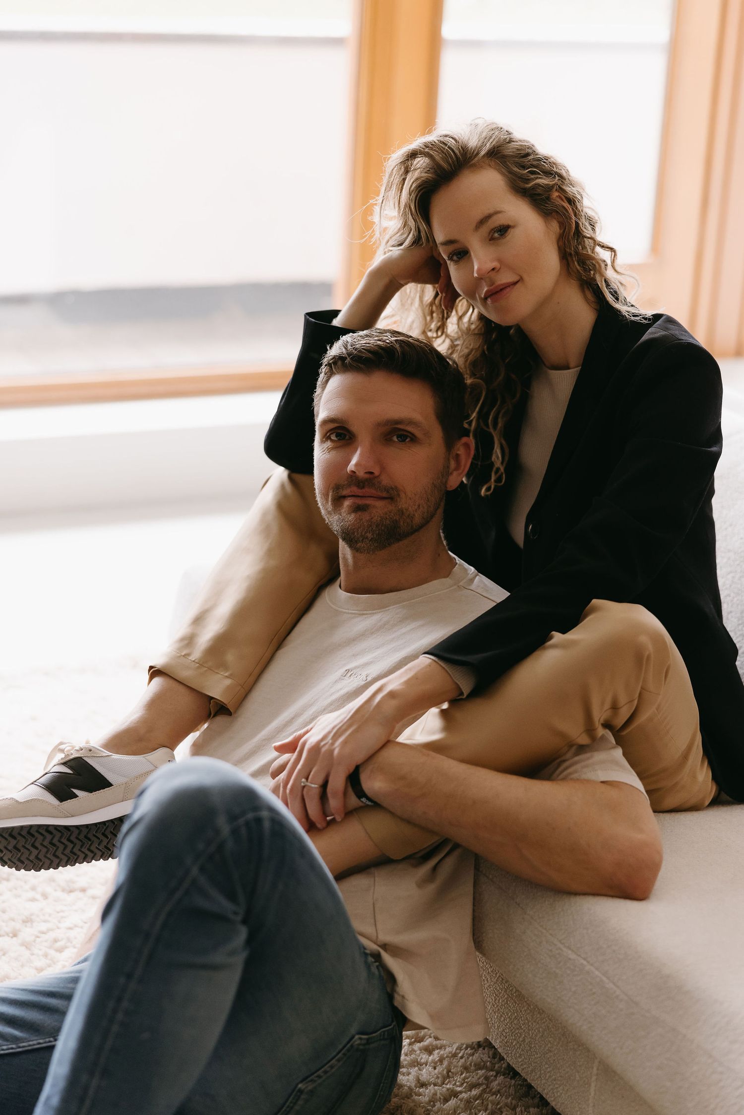 Intimate portrait of a couple lounging together on a couch in natural window light.