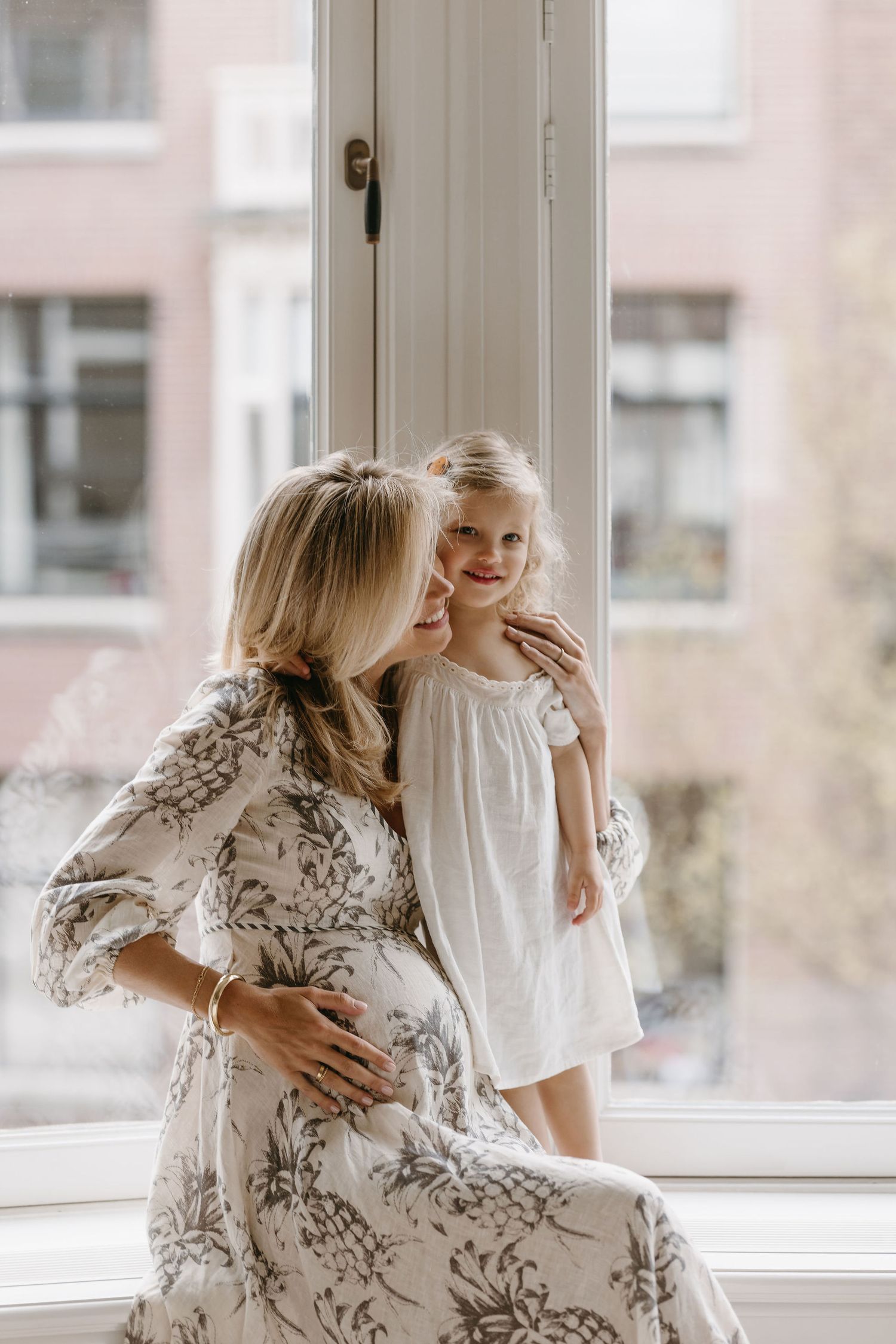 Tender maternity moment between mother and child by bright window.