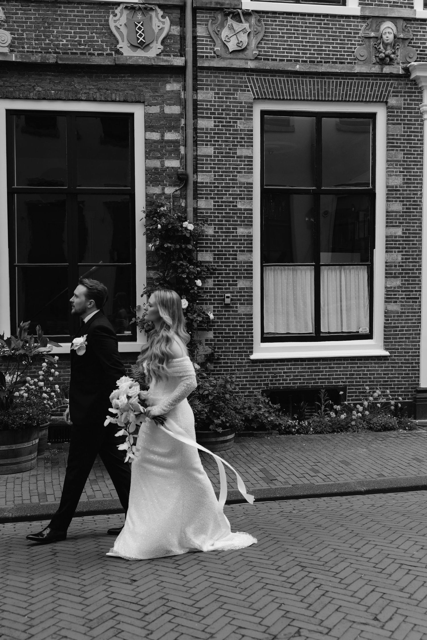 A wedding sequence showing a bride and groom walking along a brick-lined street in black and white.