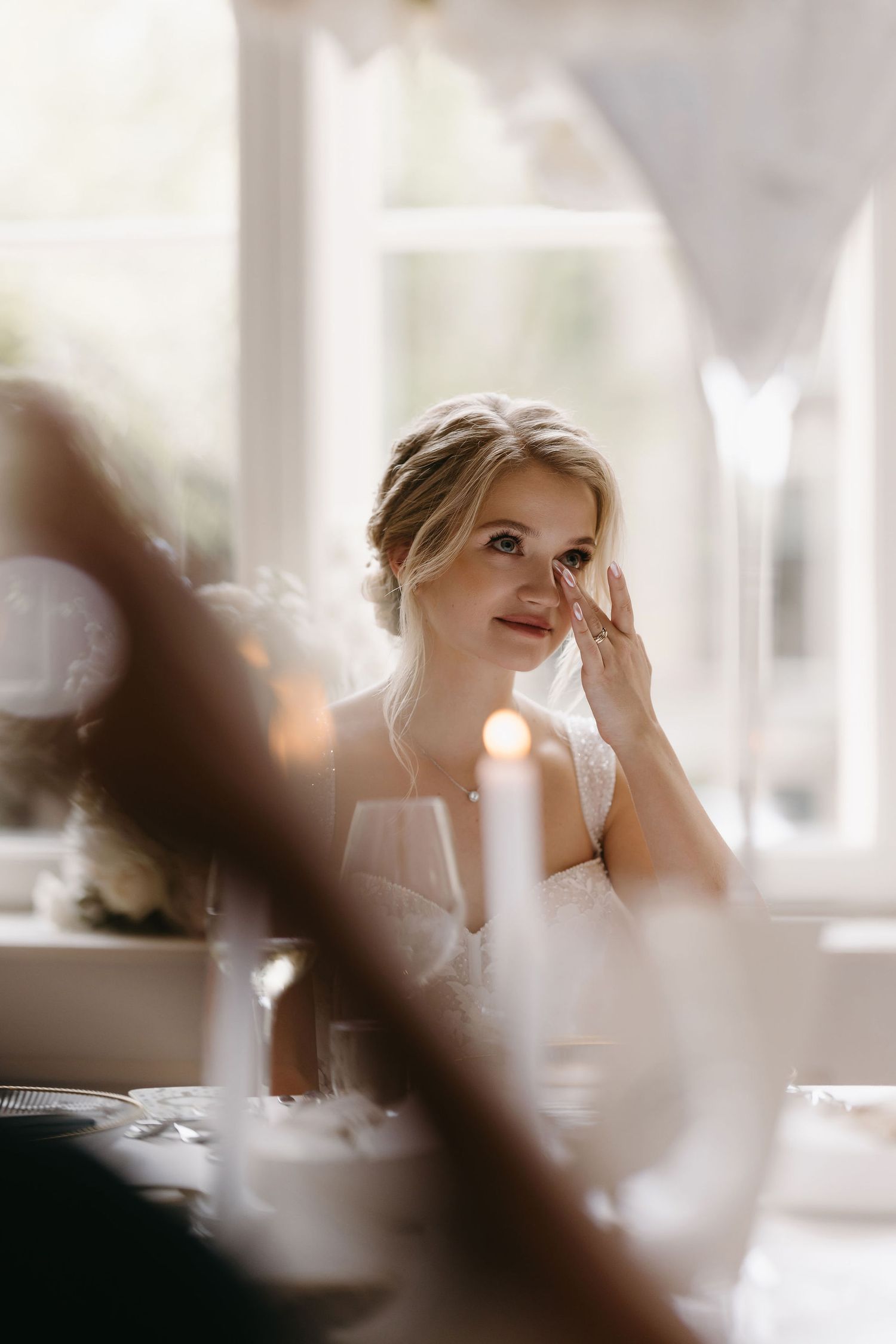 Soft, ethereal bridal preparation moment captured through natural window light.