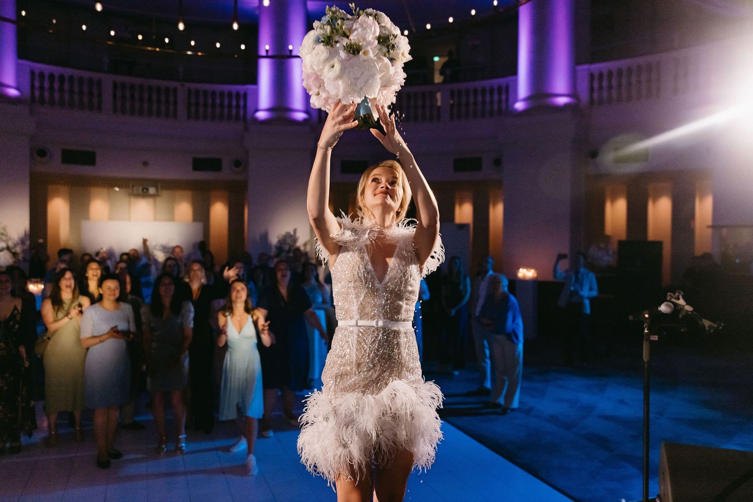 Wedding reception venue lit with purple uplighting and string lights creating a romantic atmosphere.
