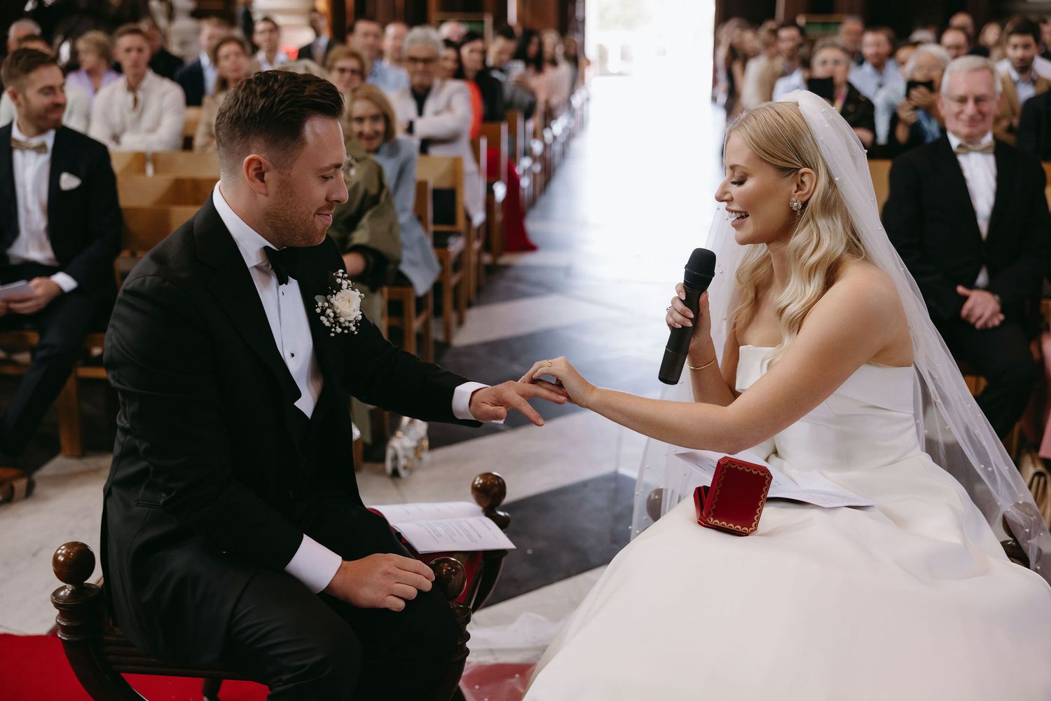 Wedding ceremony candid moments with guests seated in background during document signing.