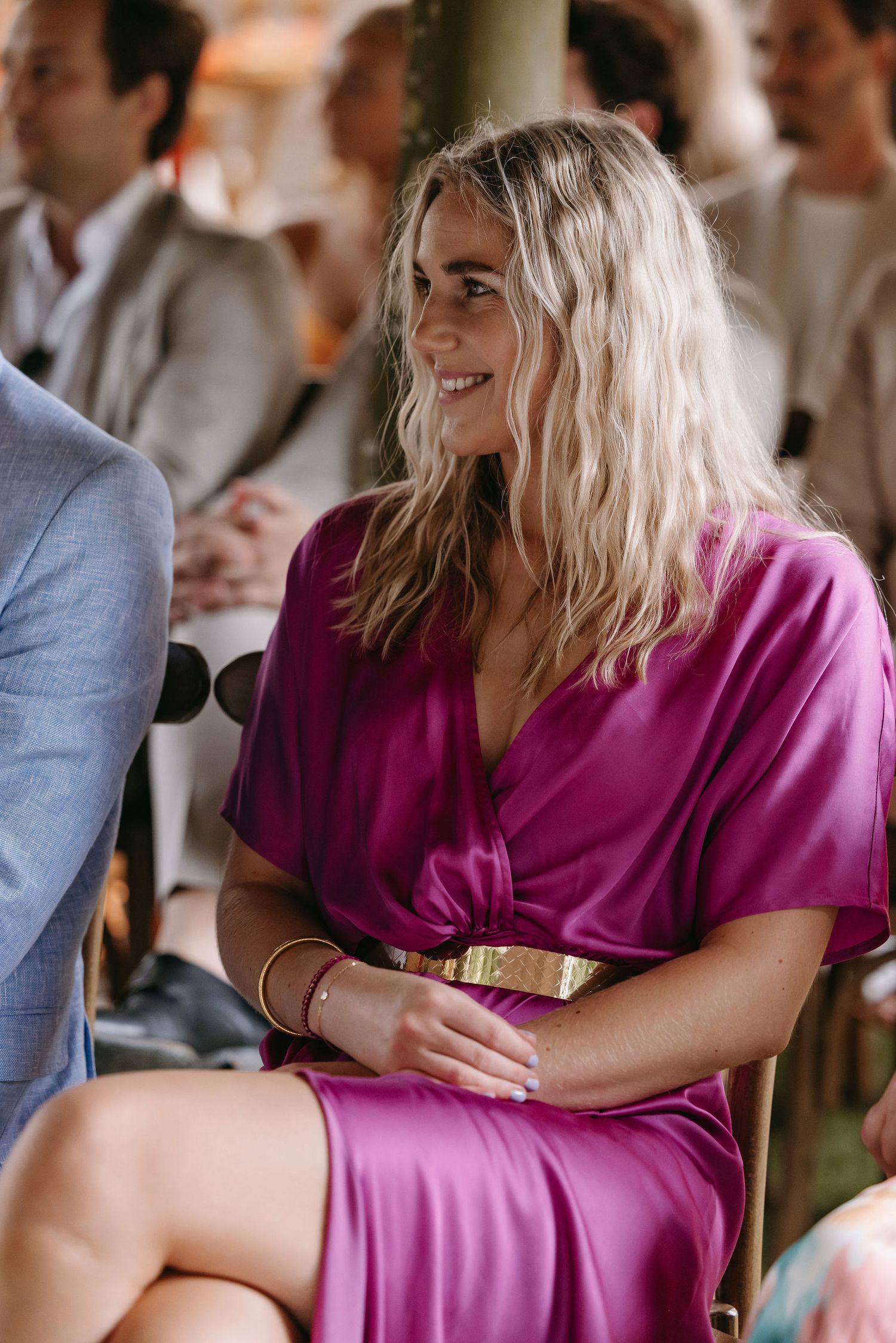 Guest in magenta dress smiling during wedding reception.
