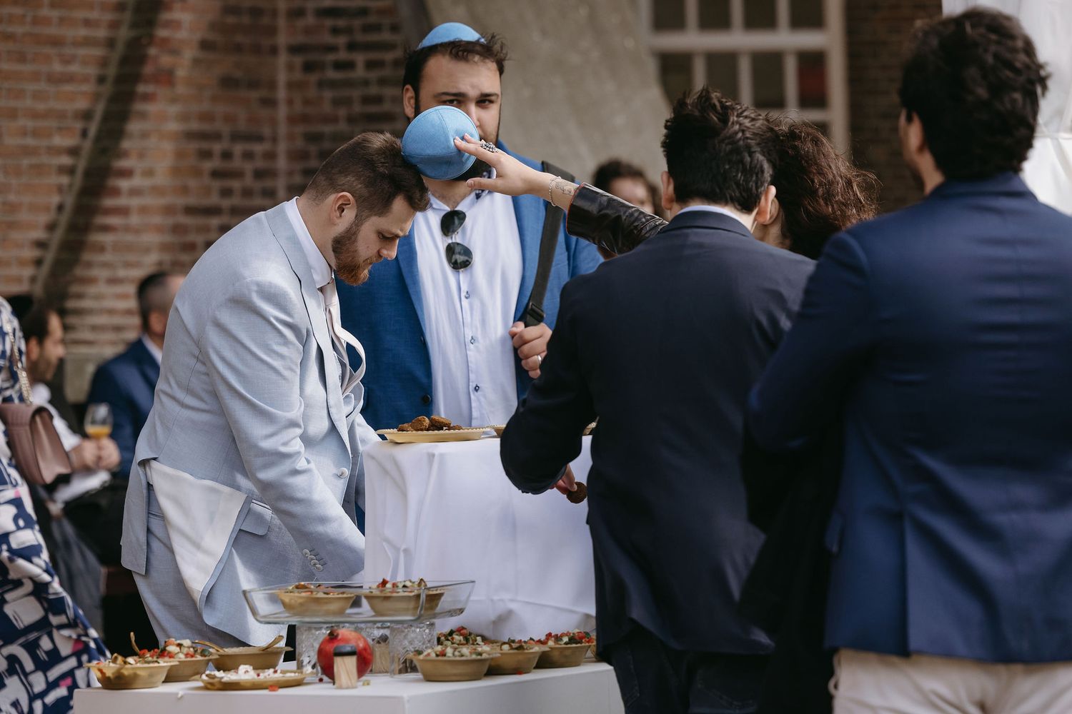 Guests gather around a buffet table at an outdoor wedding reception.