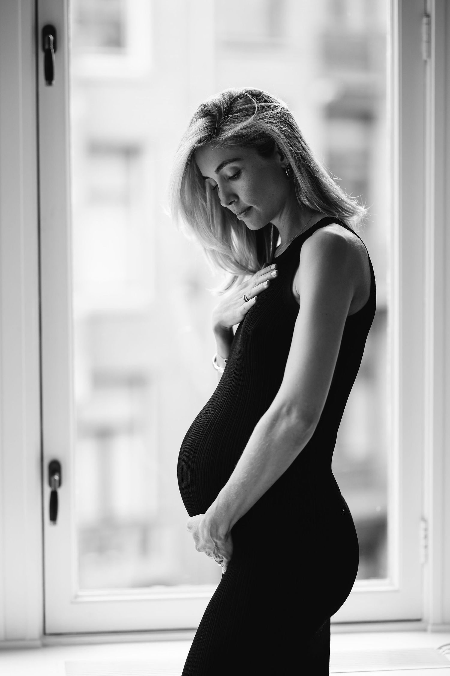 Artistic black and white maternity portrait by window.