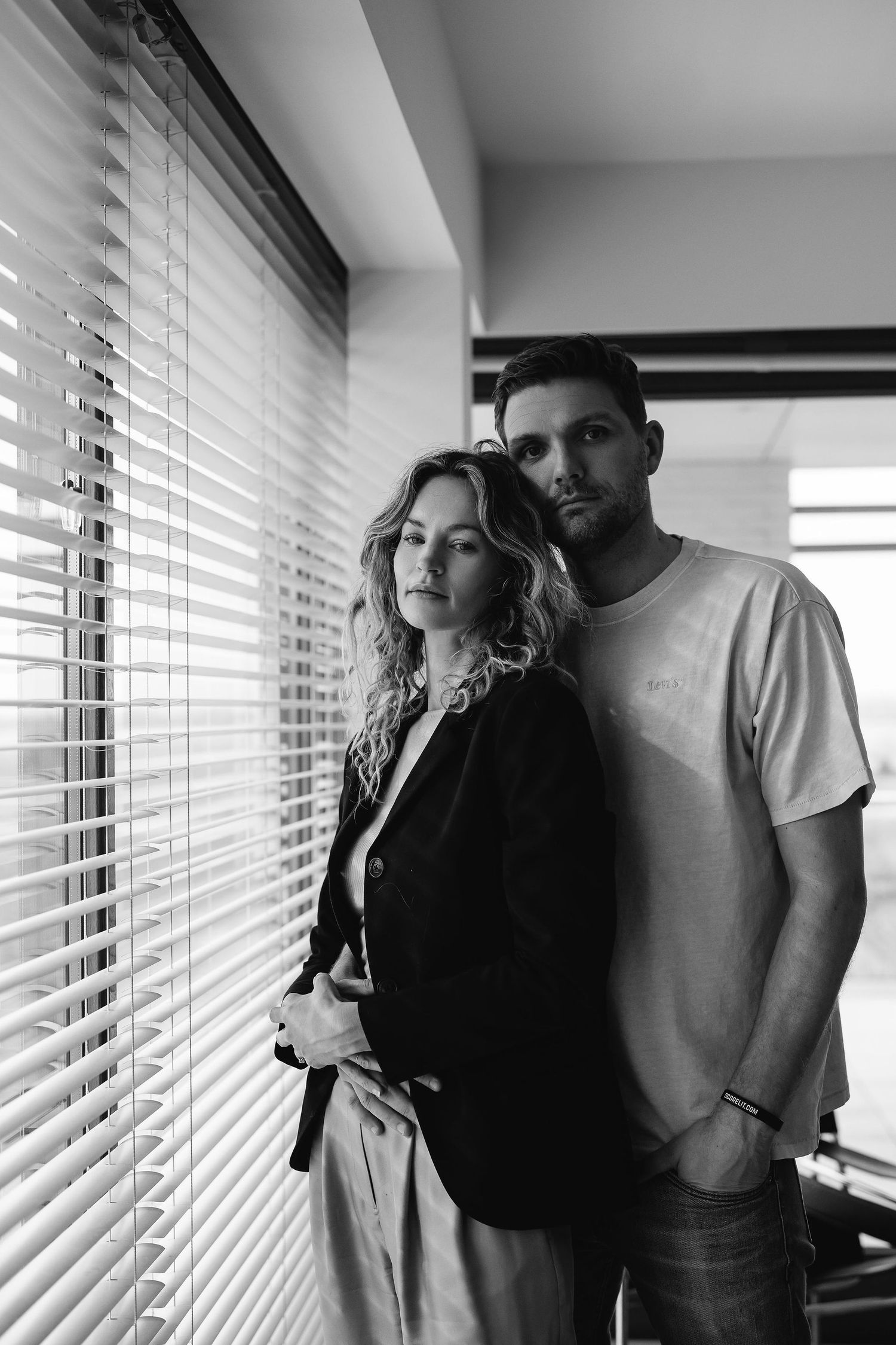 A stylish black and white portrait by venetian blinds in modern interior.