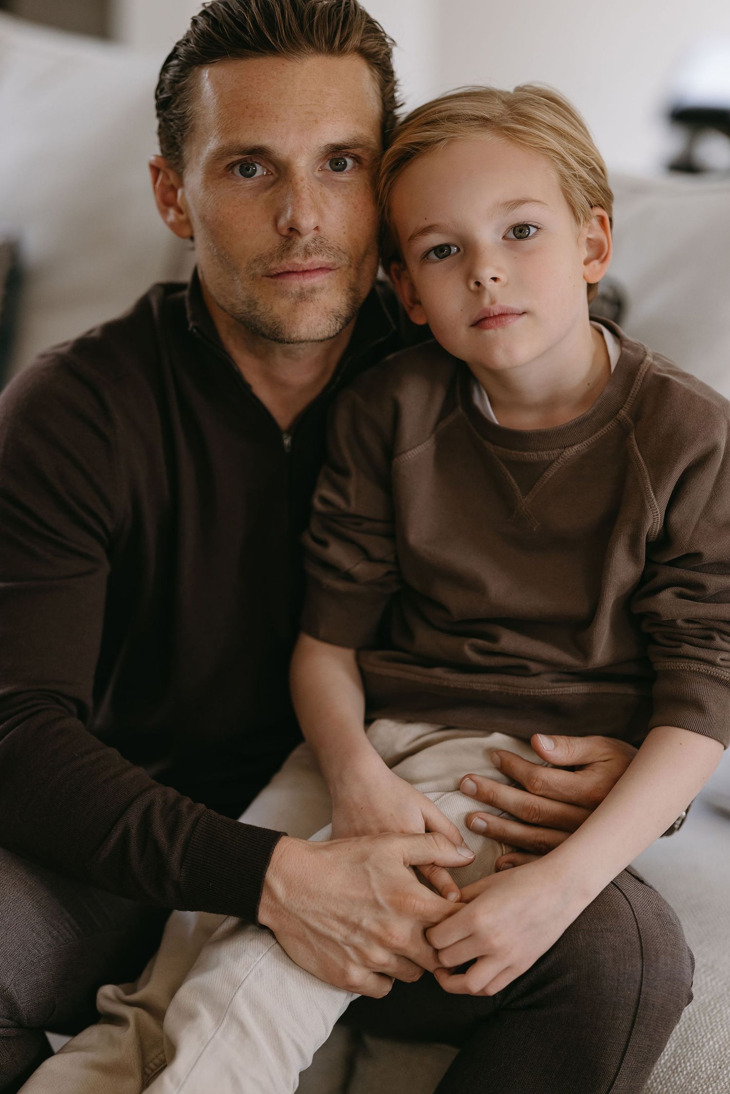 Close-up portrait of parent and child wearing matching brown sweaters.