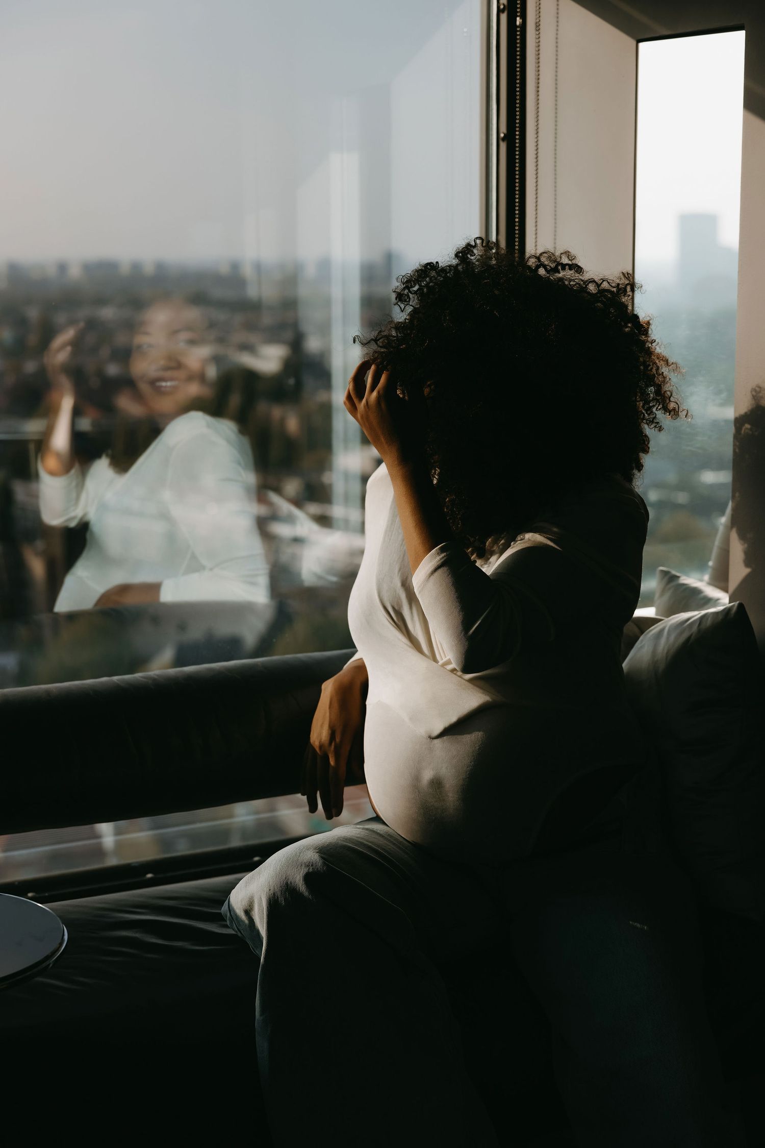 Person by a window overlooking a city skyline in natural light.