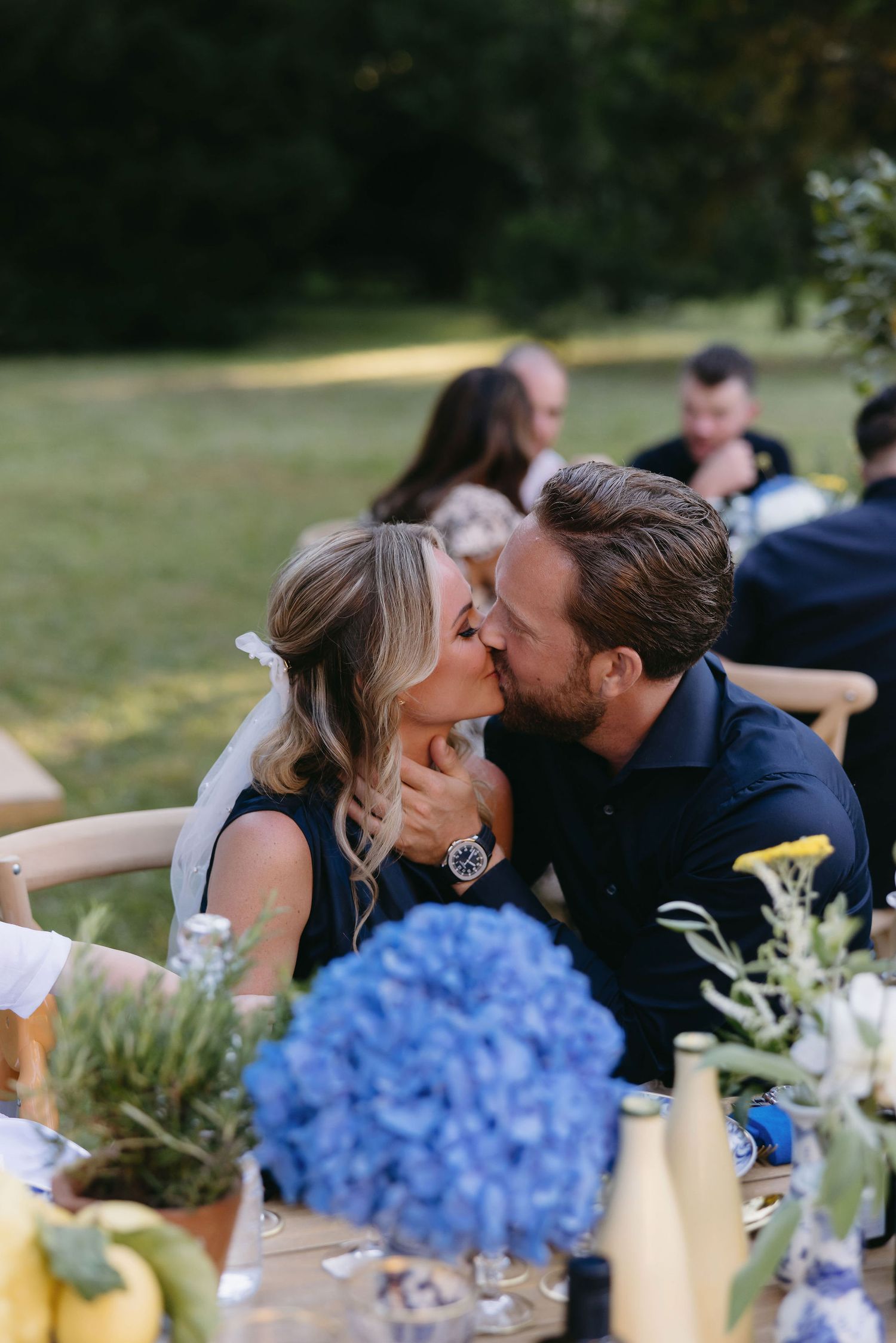 Romantic outdoor dining scene with blue hydrangeas and table decorations.