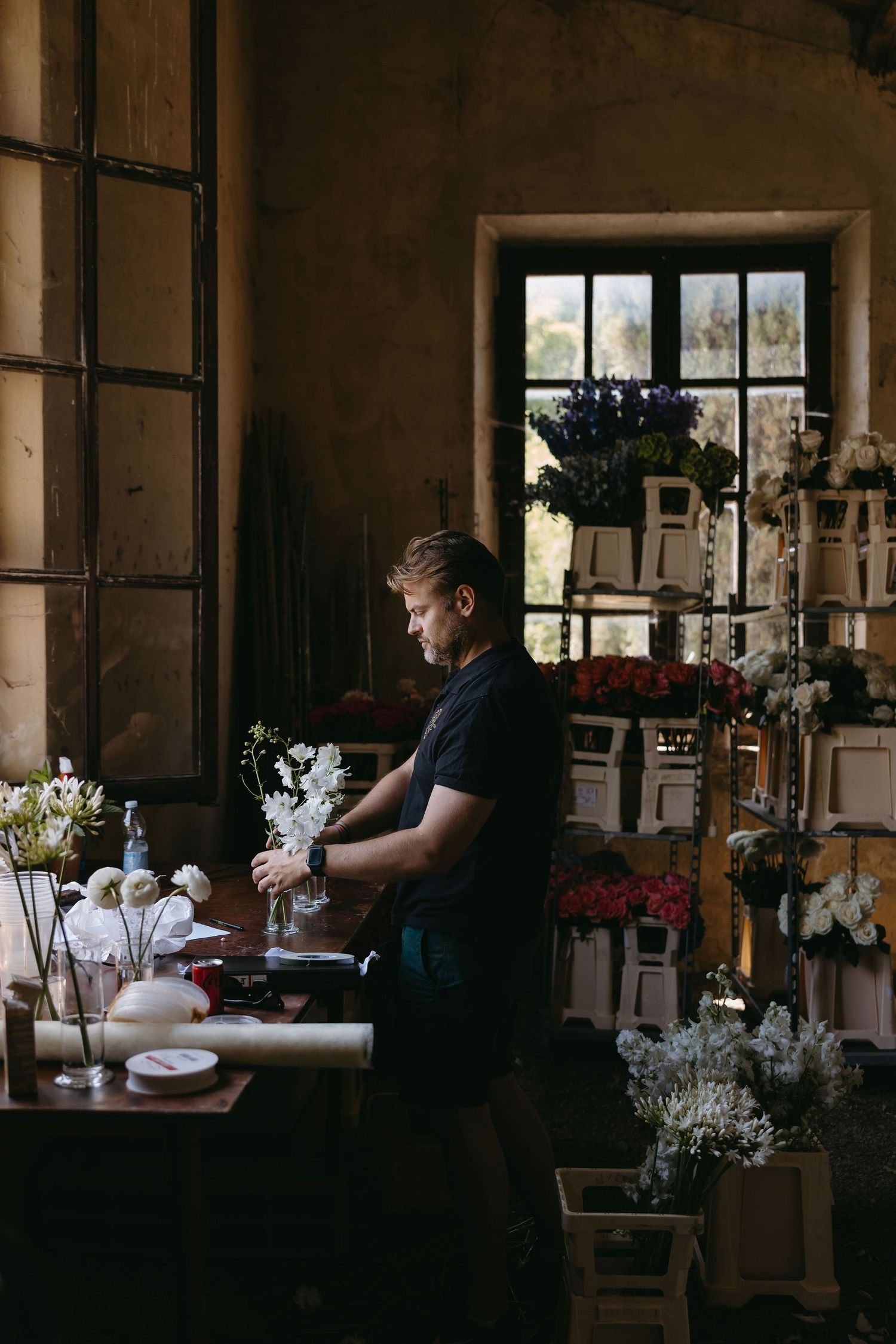 Dark atmospheric interior scene showing table settings and decorations being arranged.