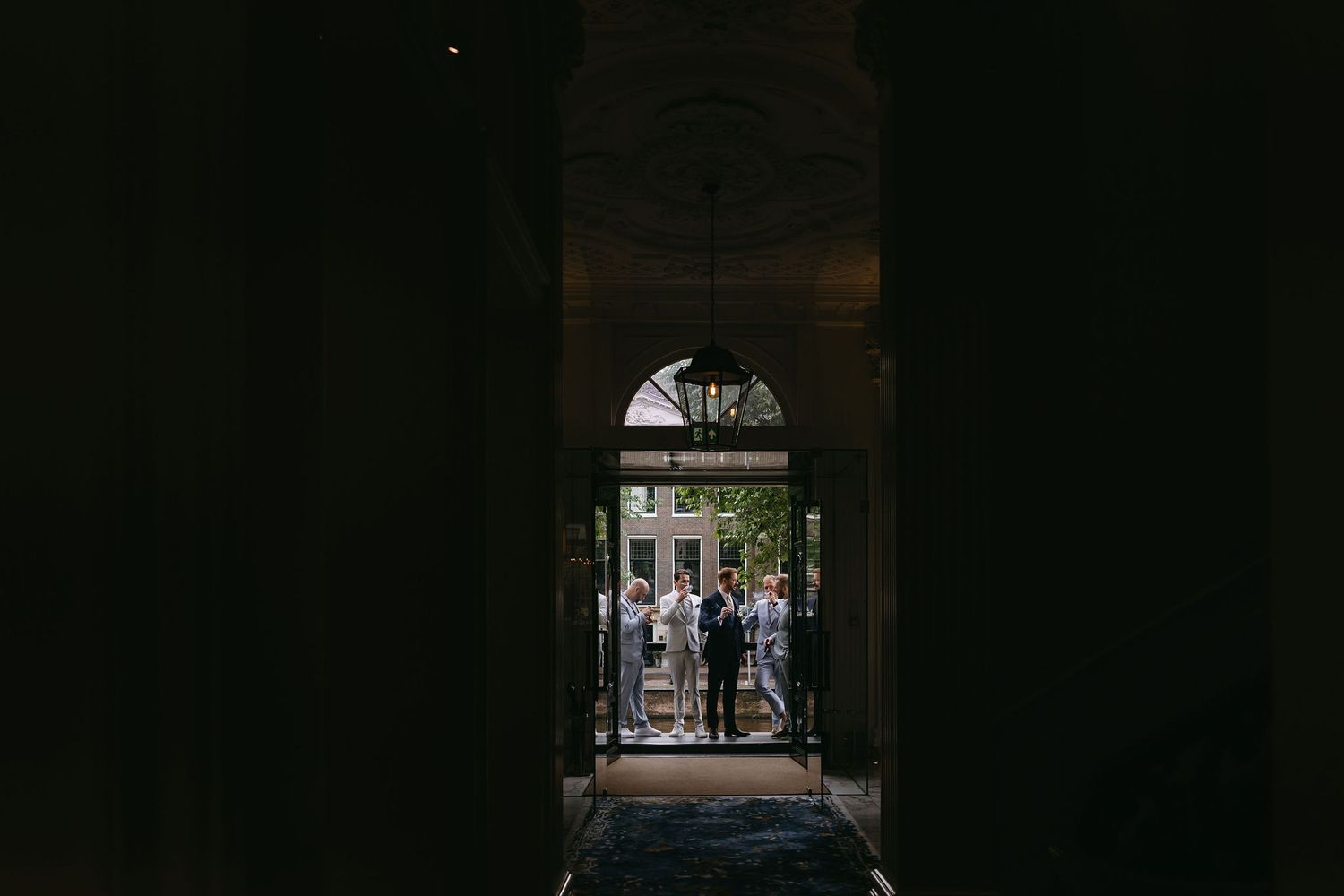 Dark interior archway frames a bright outdoor courtyard scene.