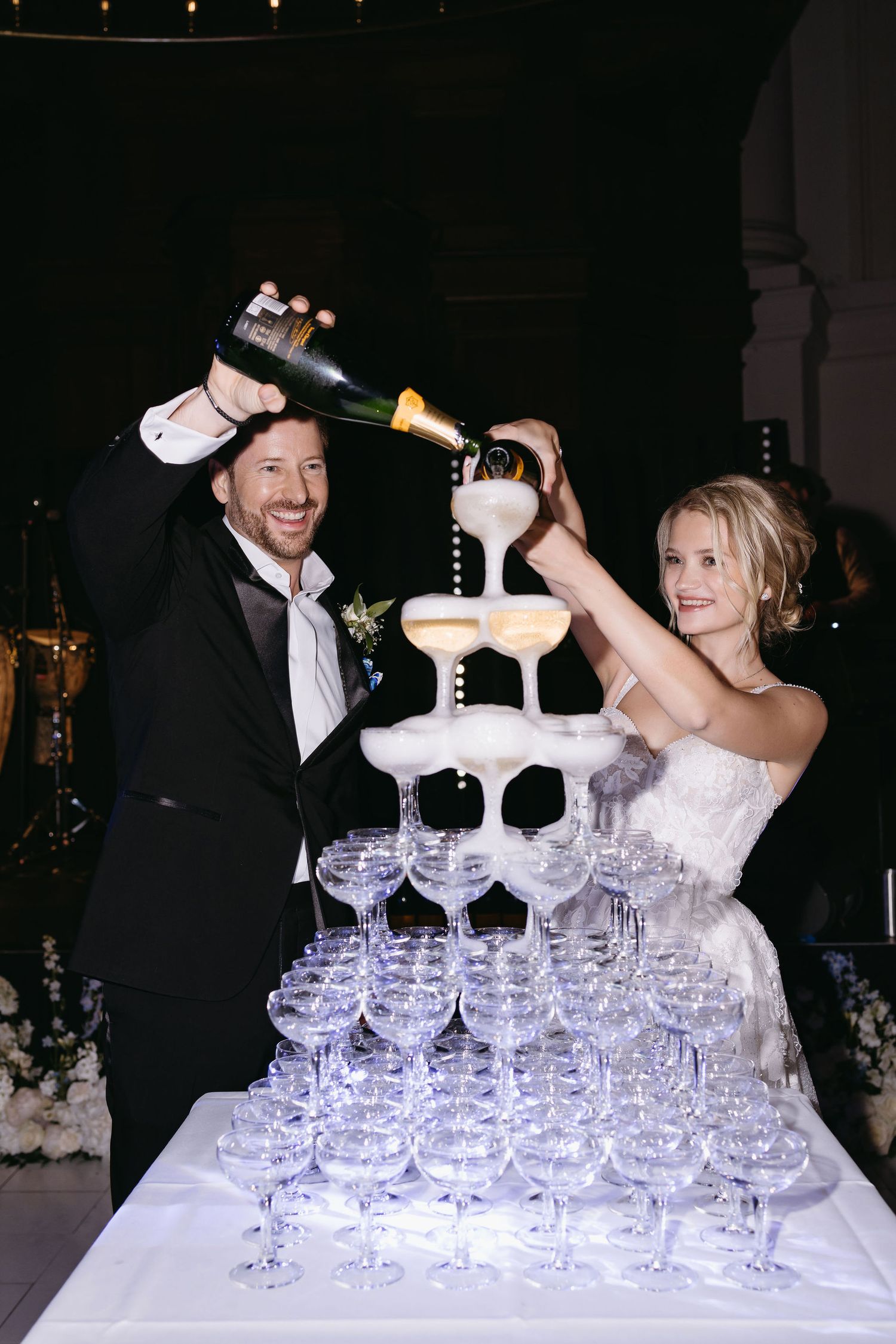 A celebratory moment as newlyweds pour champagne into a tower of glasses at their wedding reception.