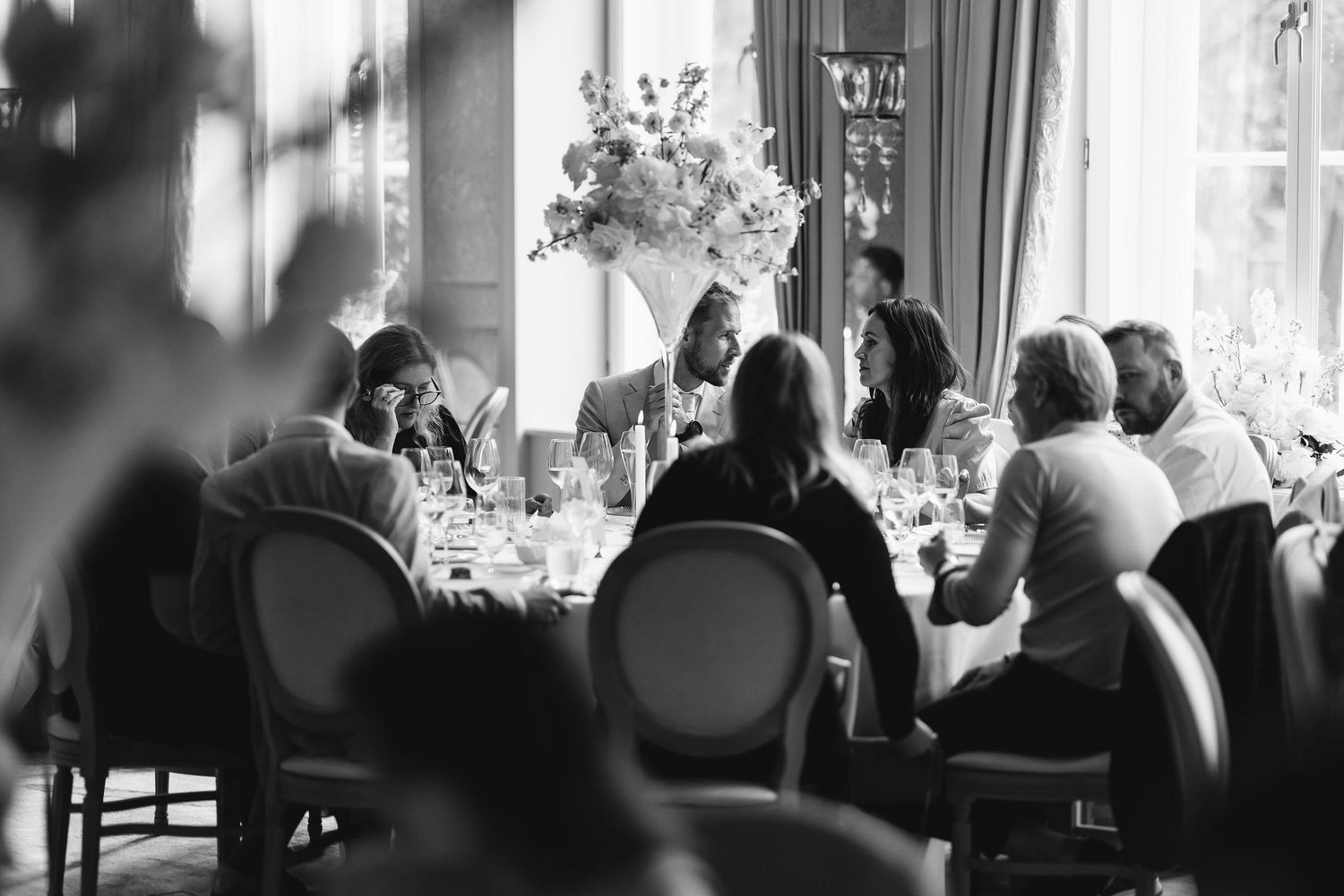 Wedding reception scene with elegant table settings and guests in silhouette.