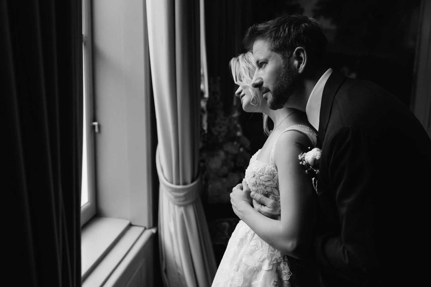 A couple shares an intimate moment while looking out a window together.