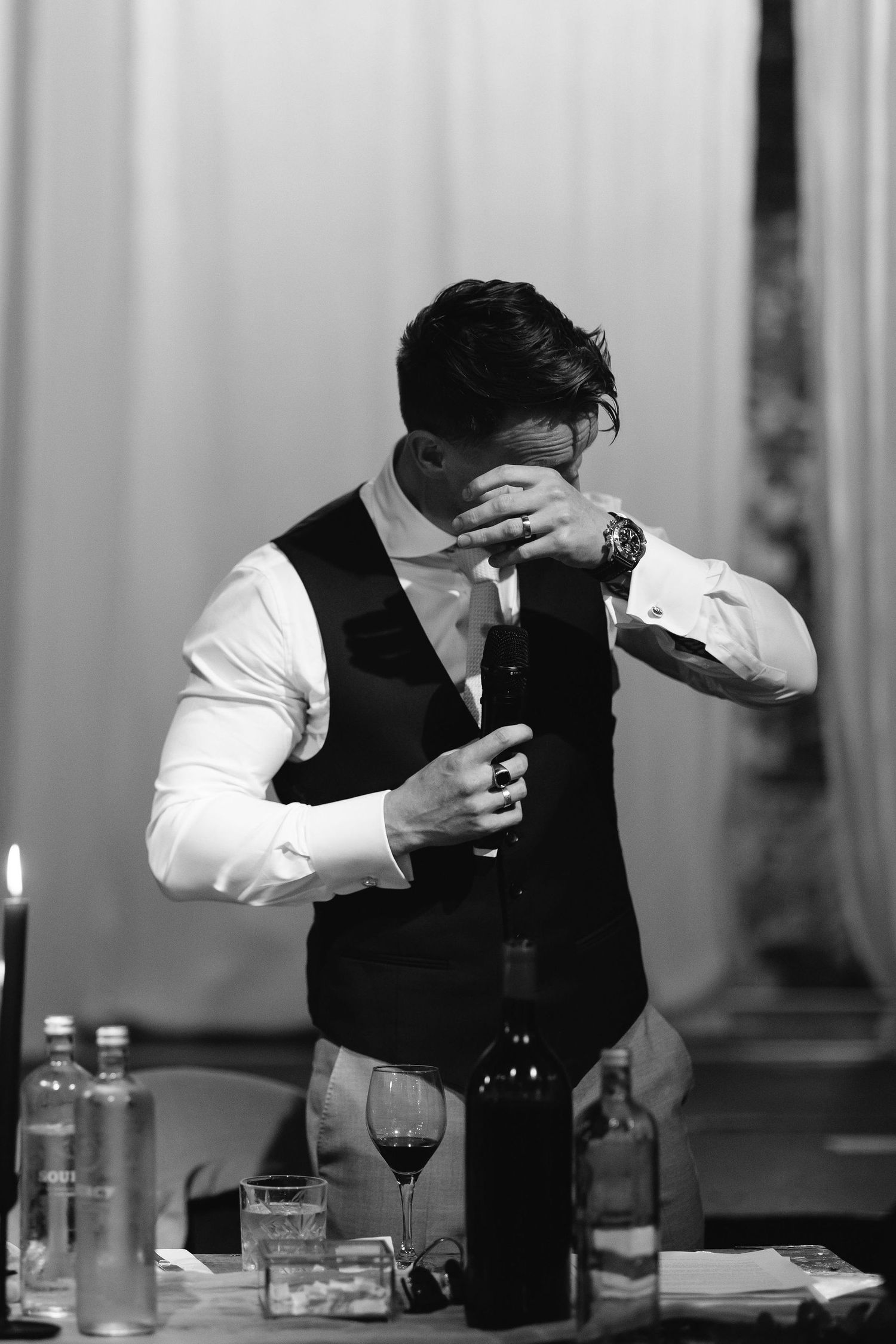 Black and white photo of someone in formal attire preparing drinks at an event.