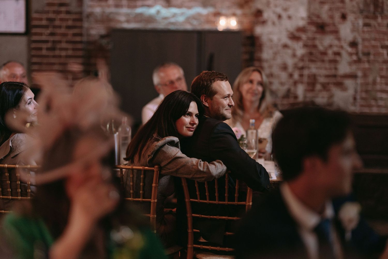 Wedding reception guests enjoying entertainment in rustic brick venue.