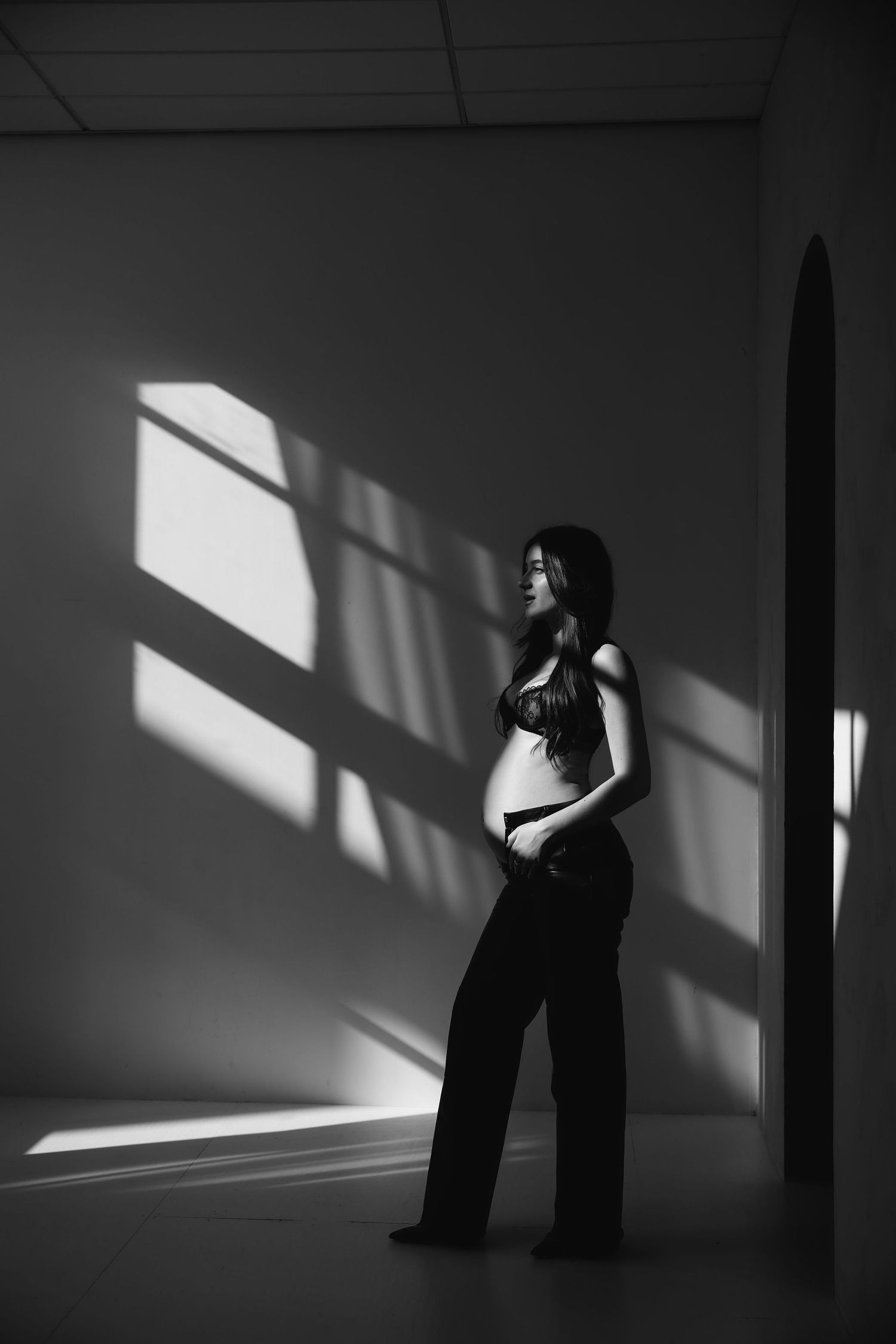 Dramatic black and white silhouette images of a figure against stark white walls with angular shadows.