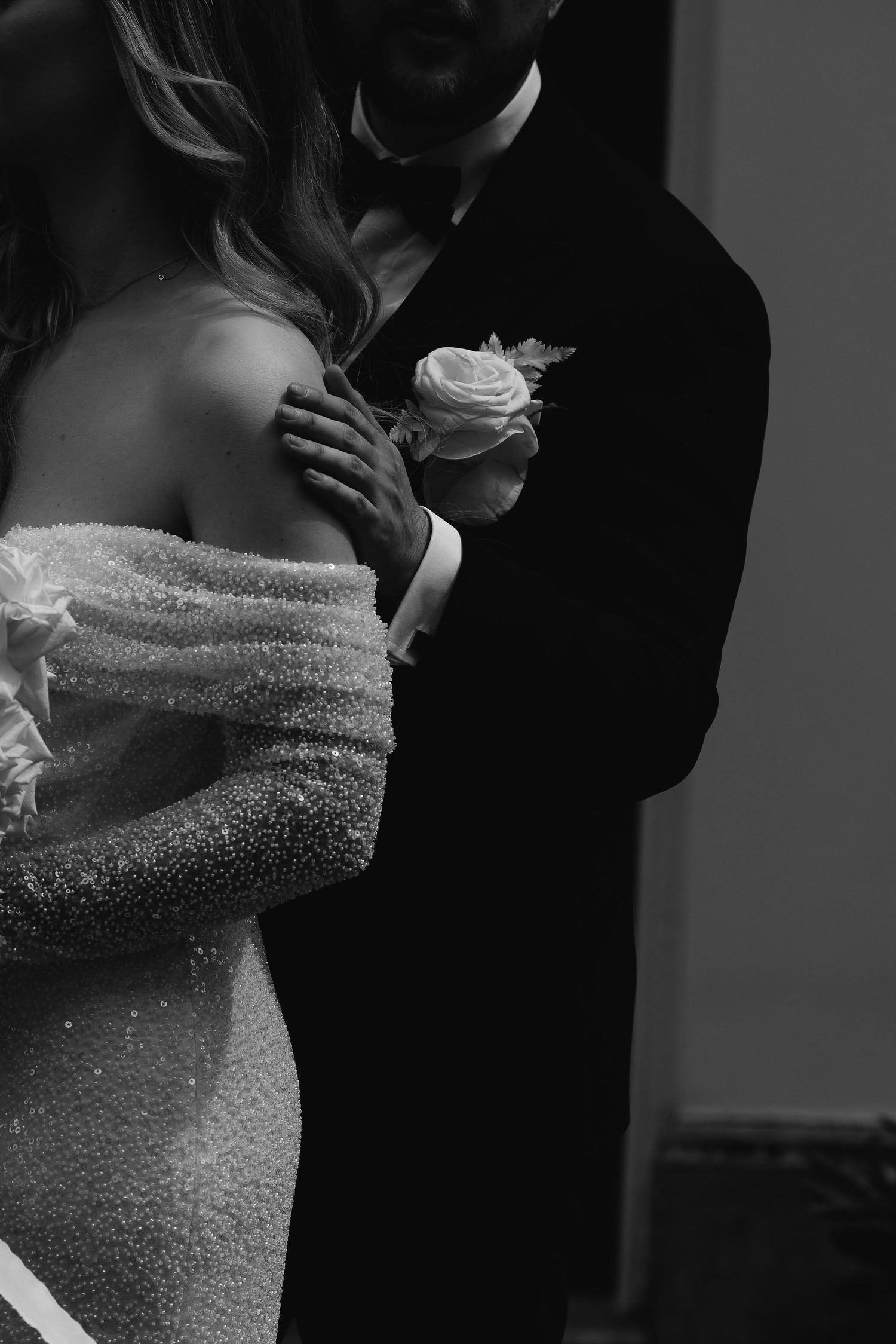 A romantic black and white wedding moment shows a couple embracing in formal attire with a sparkly dress detail.