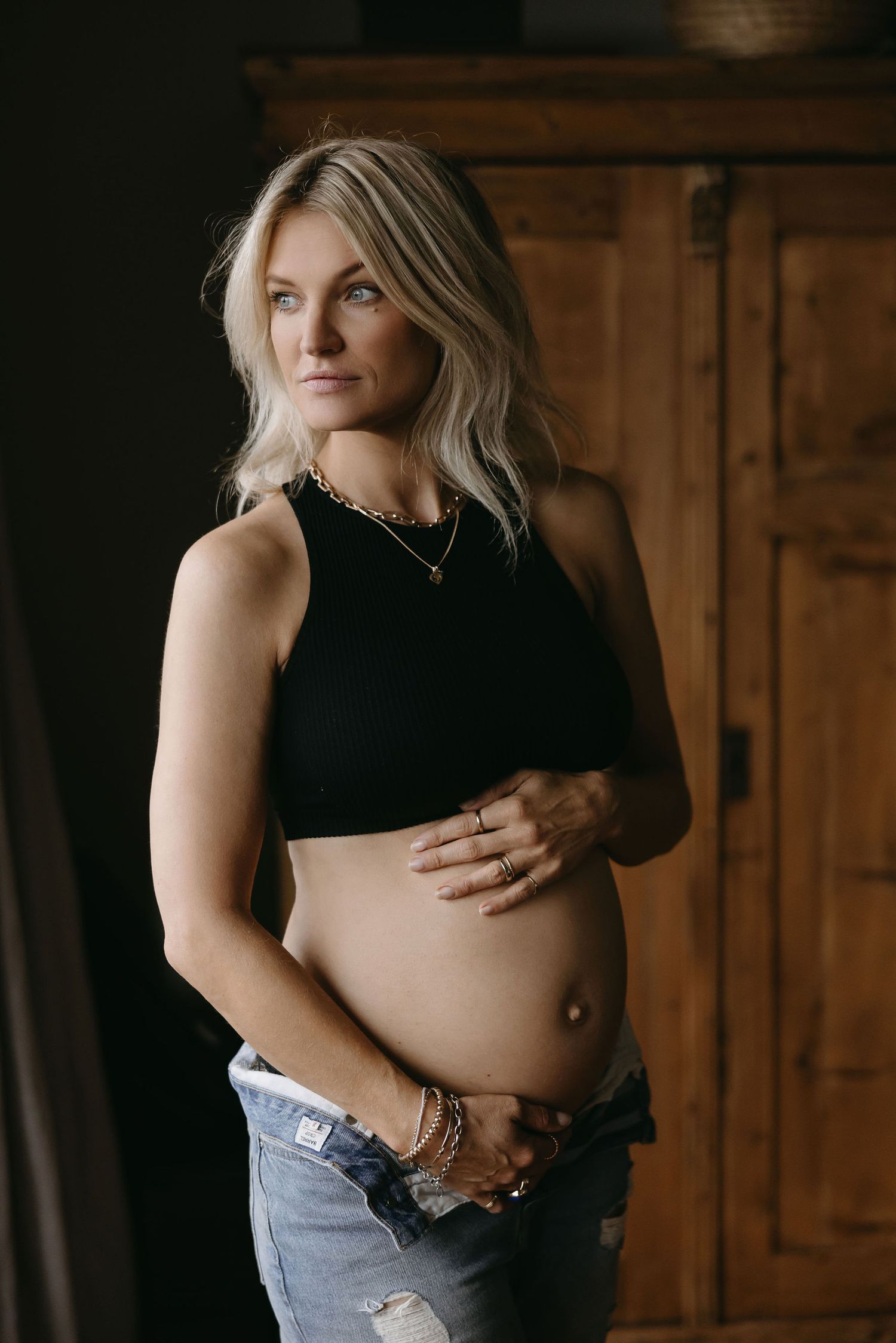Intimate maternity portraits with denim and black clothing against wooden backdrop.