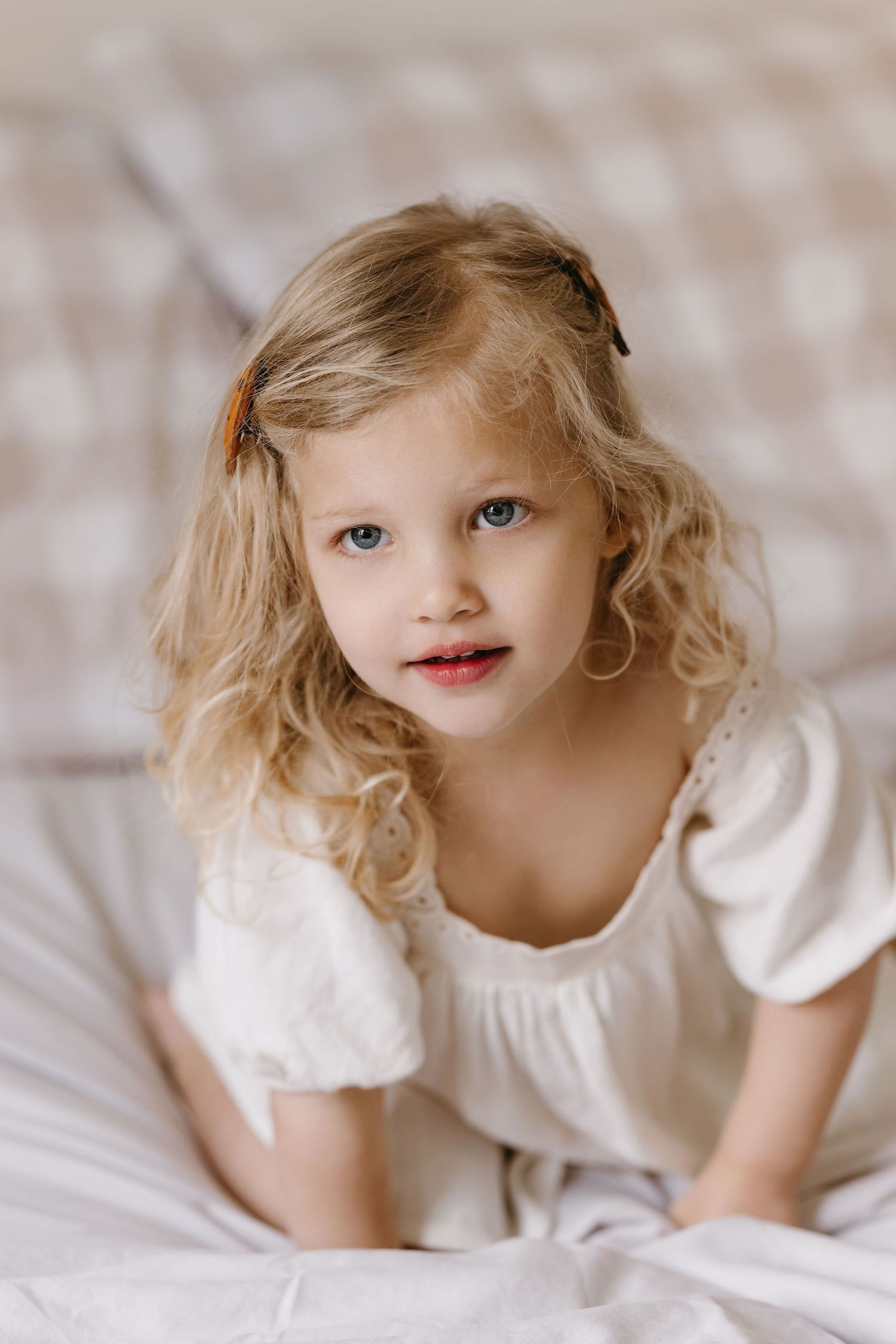 Close-up portraits of a small child in a white dress against a soft background.