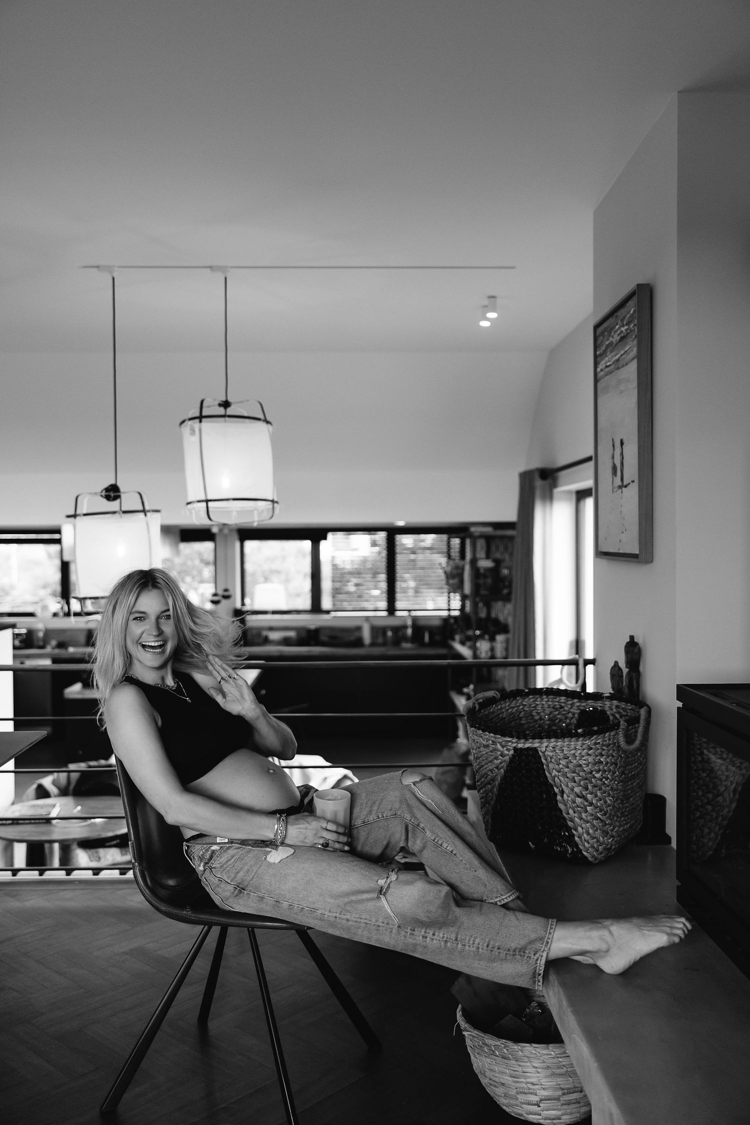 Black and white maternity portrait in modern interior with pendant lights.