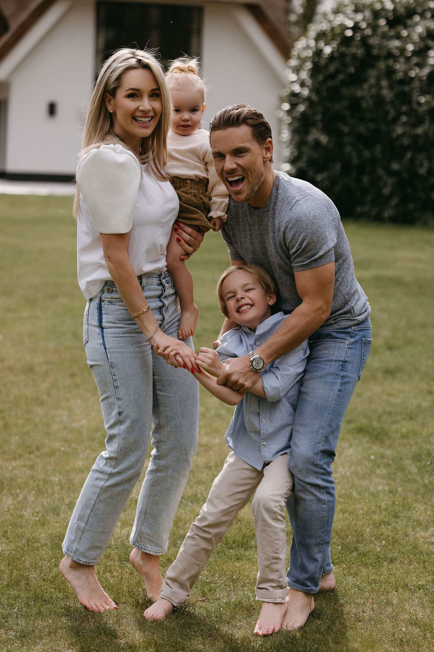 Candid family photo of playful outdoor moment on lawn in casual wear.