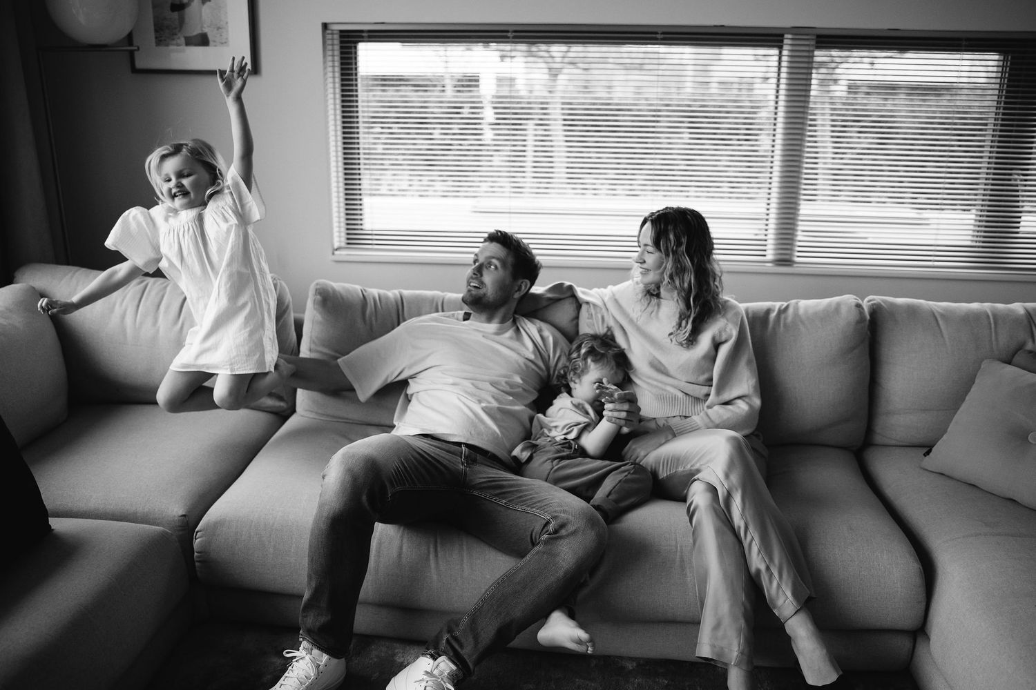 A relaxed family moment on a grey sectional sofa with natural window light.
