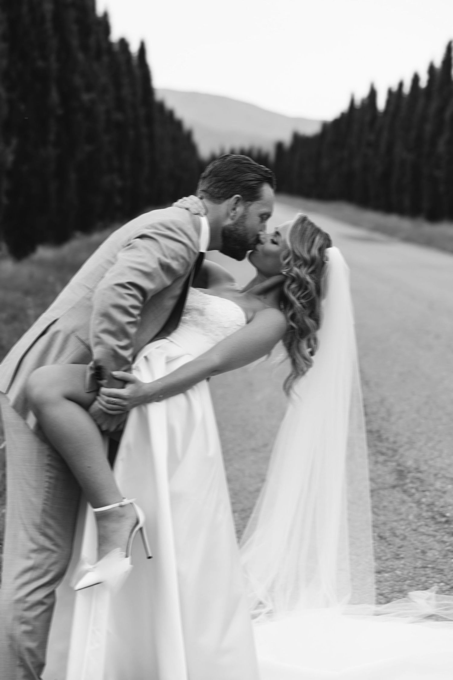 Romantic wedding portrait taken on a mountain road surrounded by pine trees.