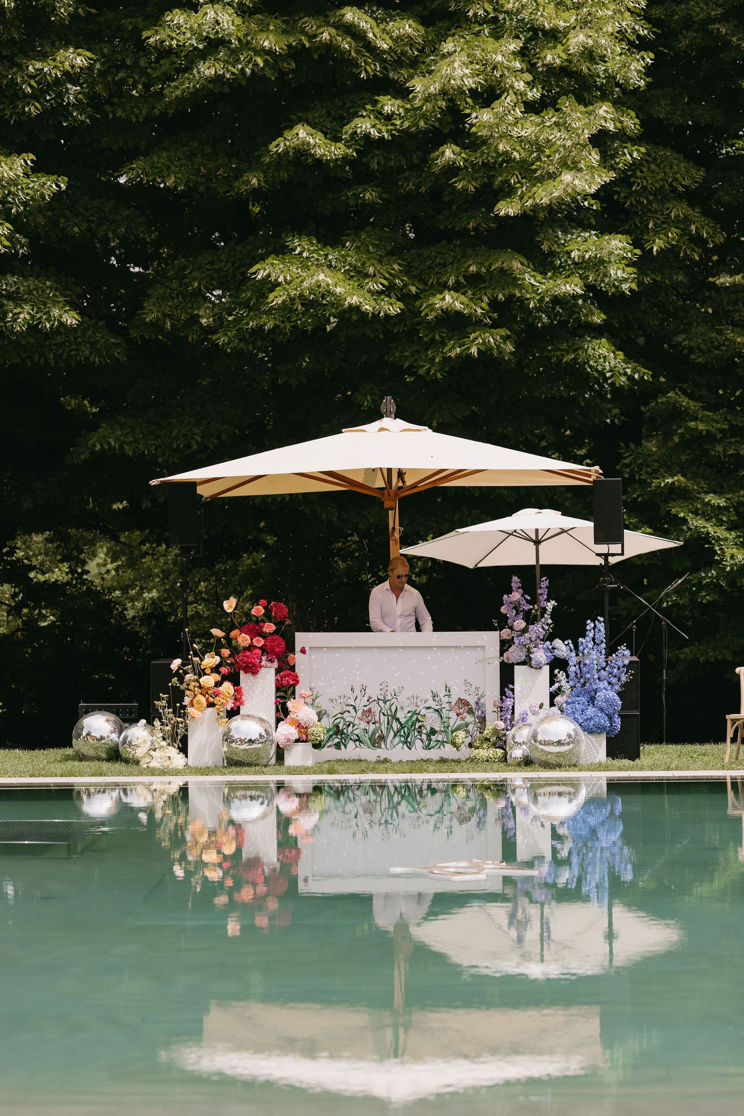 An elegant poolside bar setup with white umbrellas and floral arrangements.
