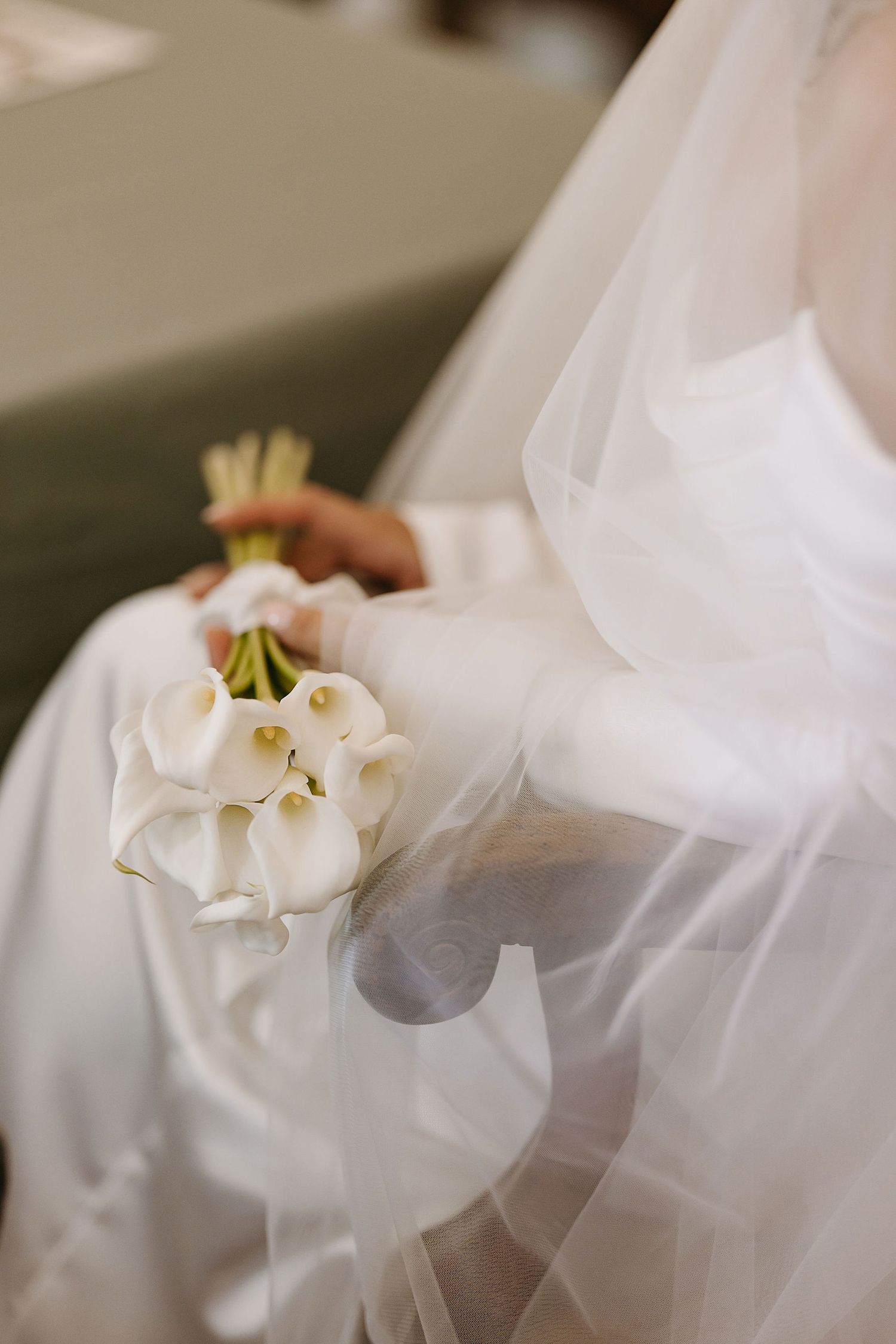 Detail shot of a white calla lily bridal bouquet with flowing veil.