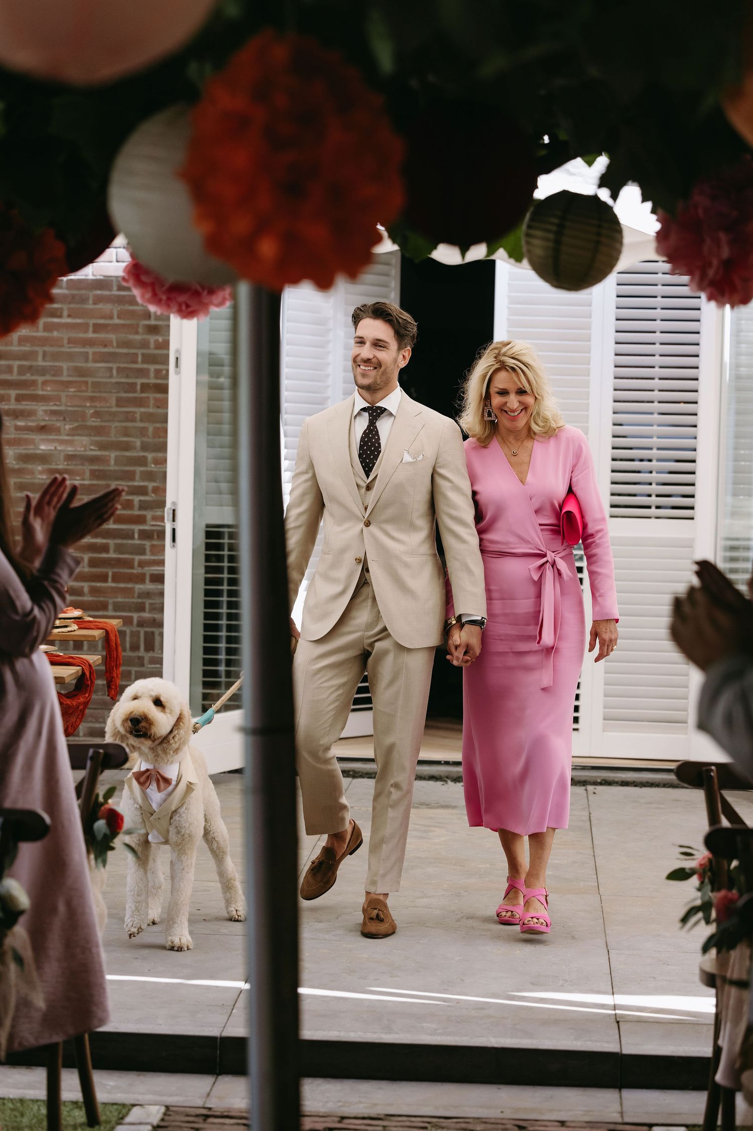 Wedding guests walking through covered patio area decorated with red paper lanterns.