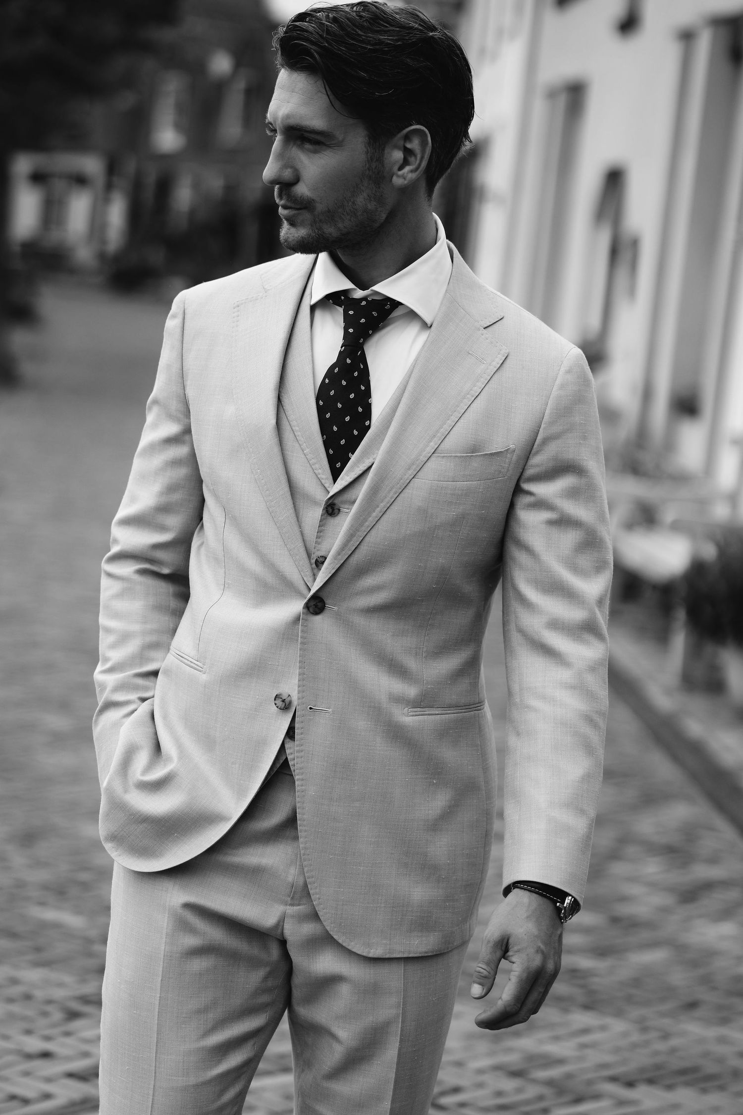 Black and white images showing details of a groom in a light colored suit and polka dot tie.