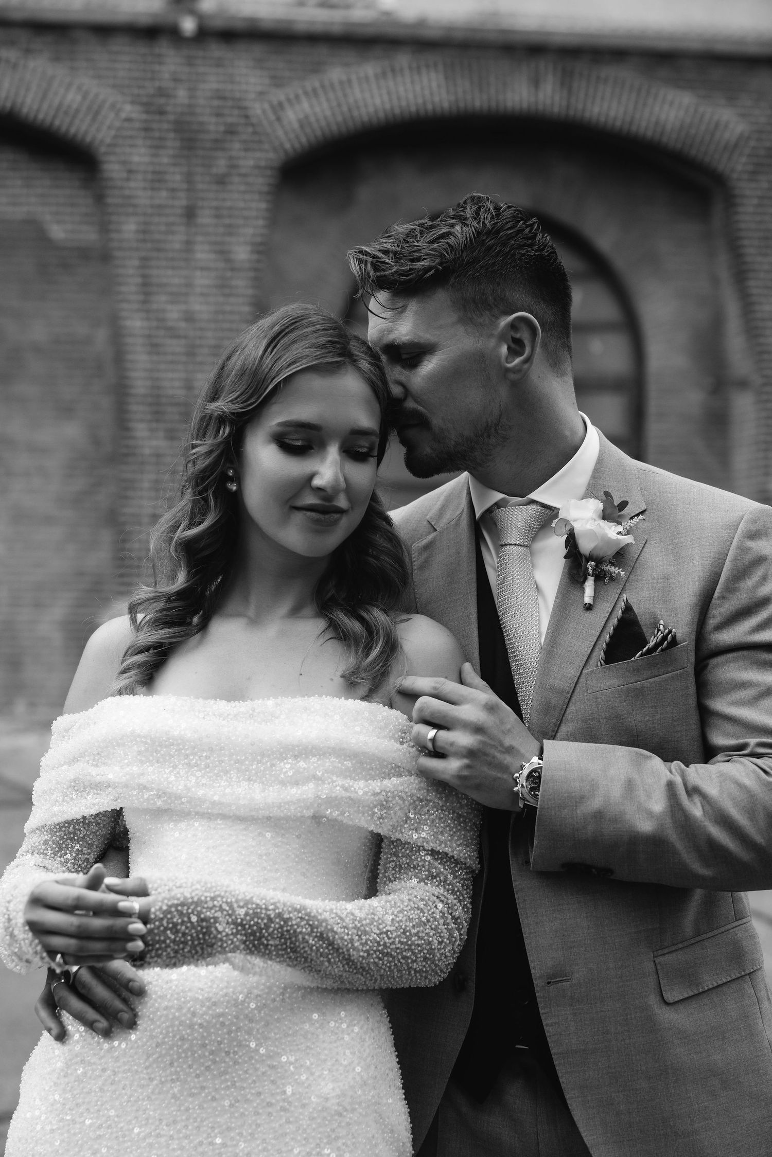 Intimate black and white portraits of a couple sharing tender moments against brick walls.