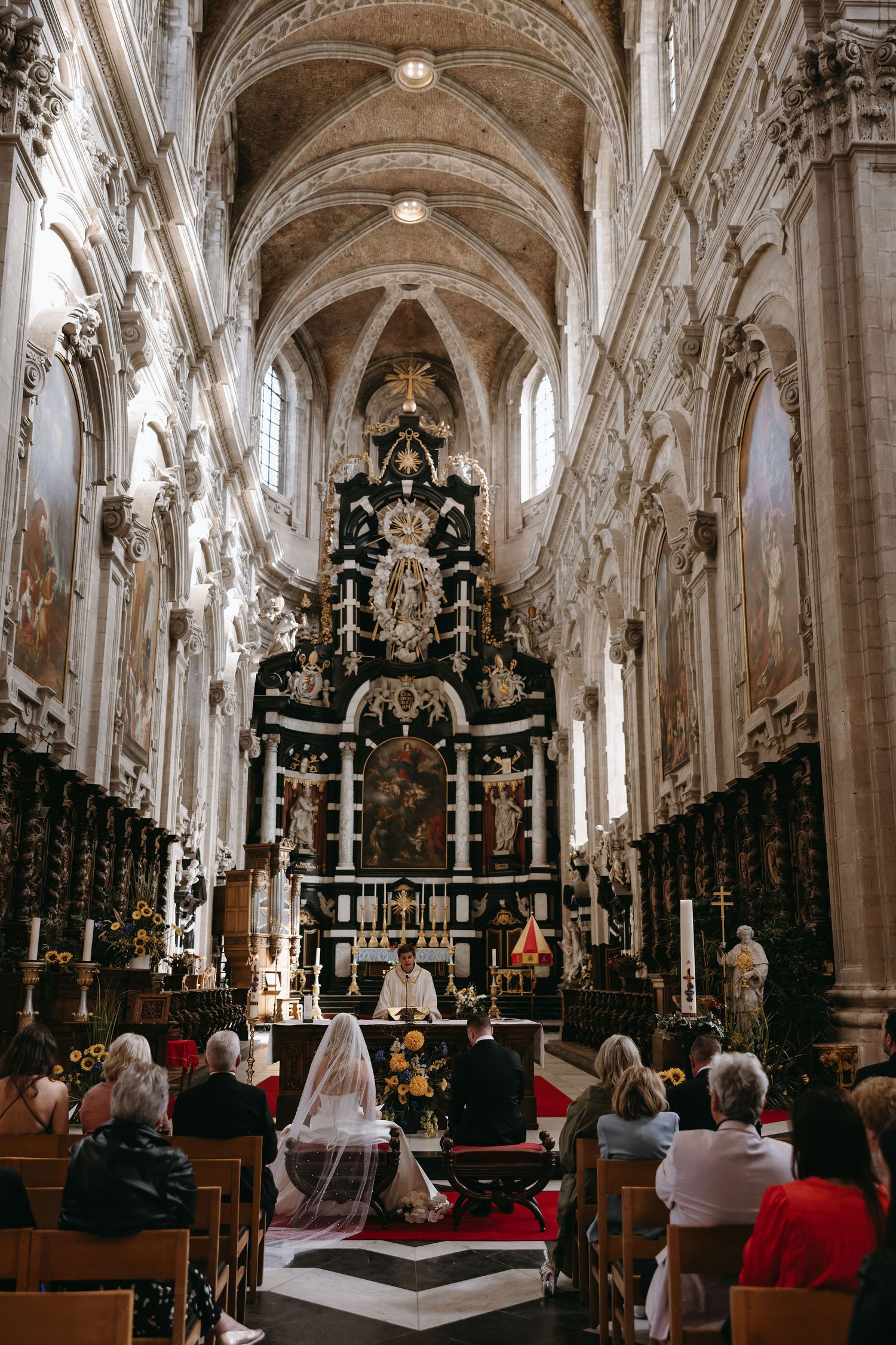 A ornate cathedral interior with vaulted ceilings and elaborate altar during a wedding ceremony.