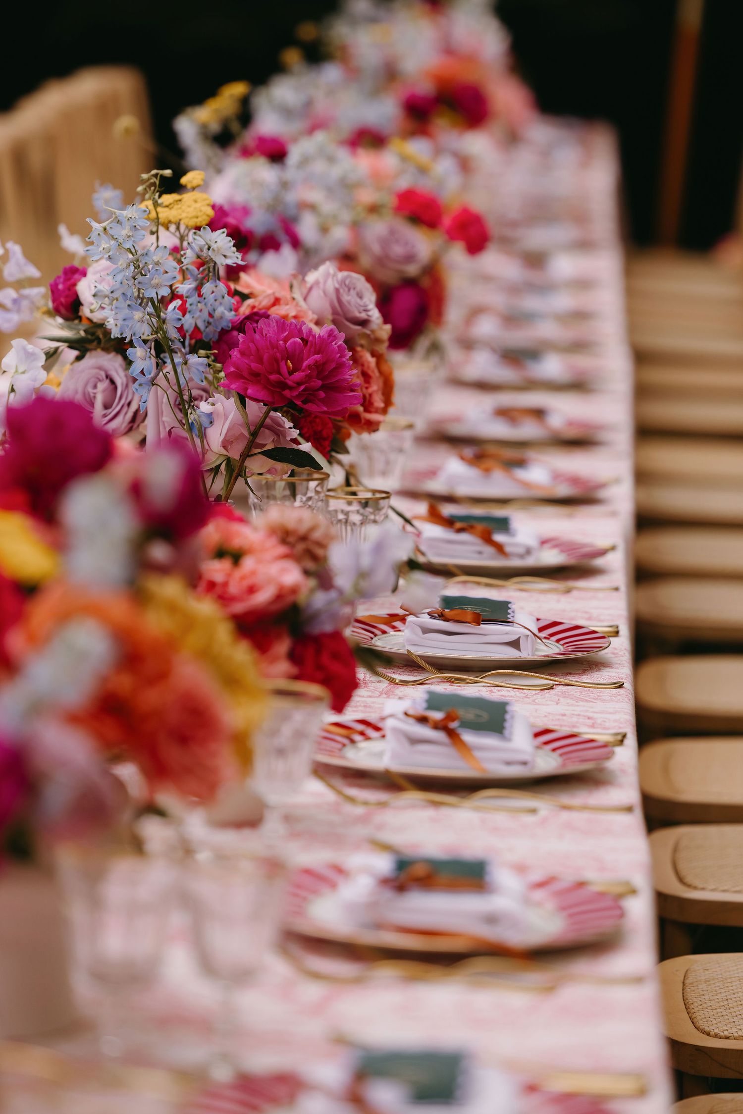 Elegant wedding table setting with vibrant pink and purple floral centerpieces and place settings.