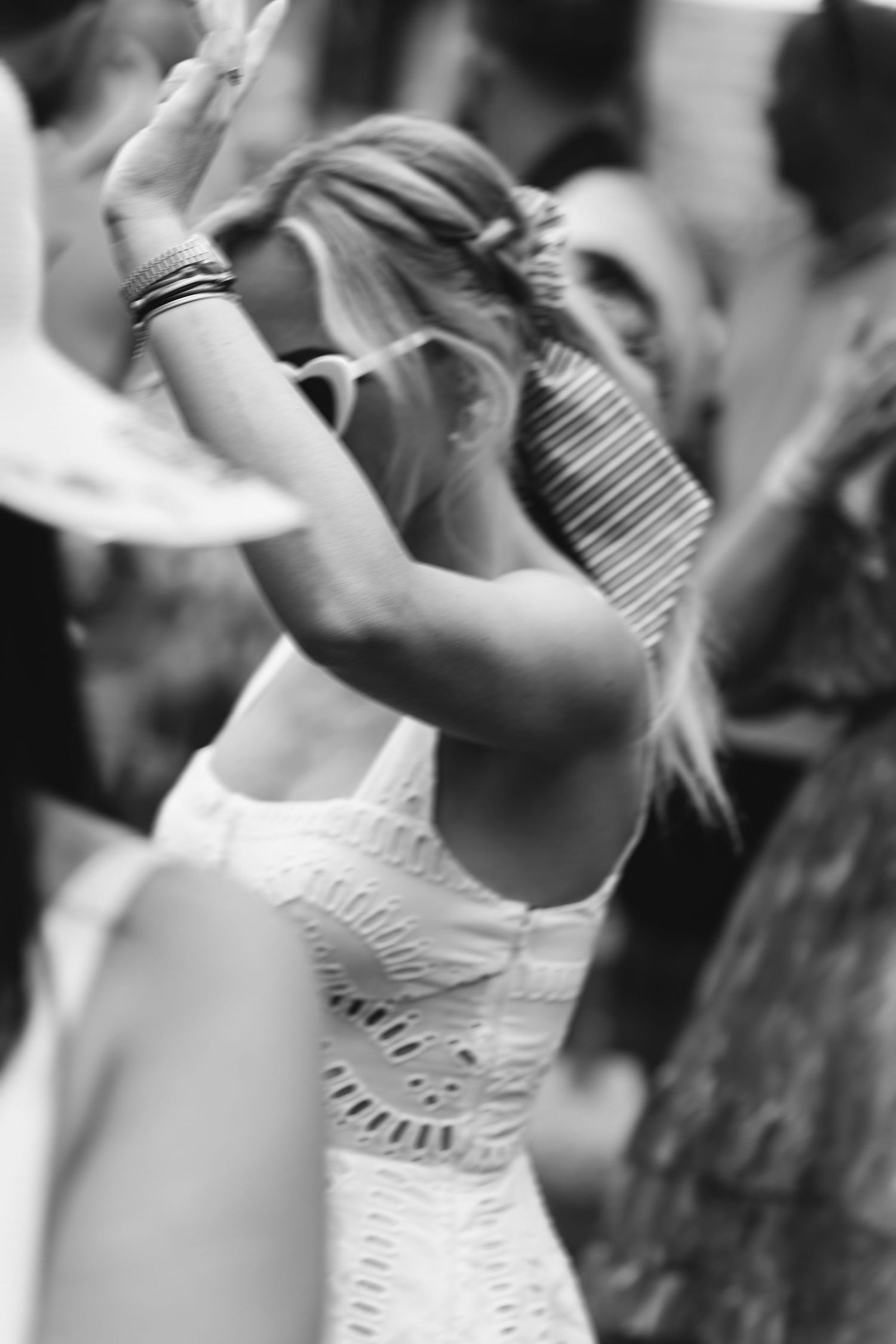 A black and white photo capturing a joyful moment of dancing in a white lace dress.