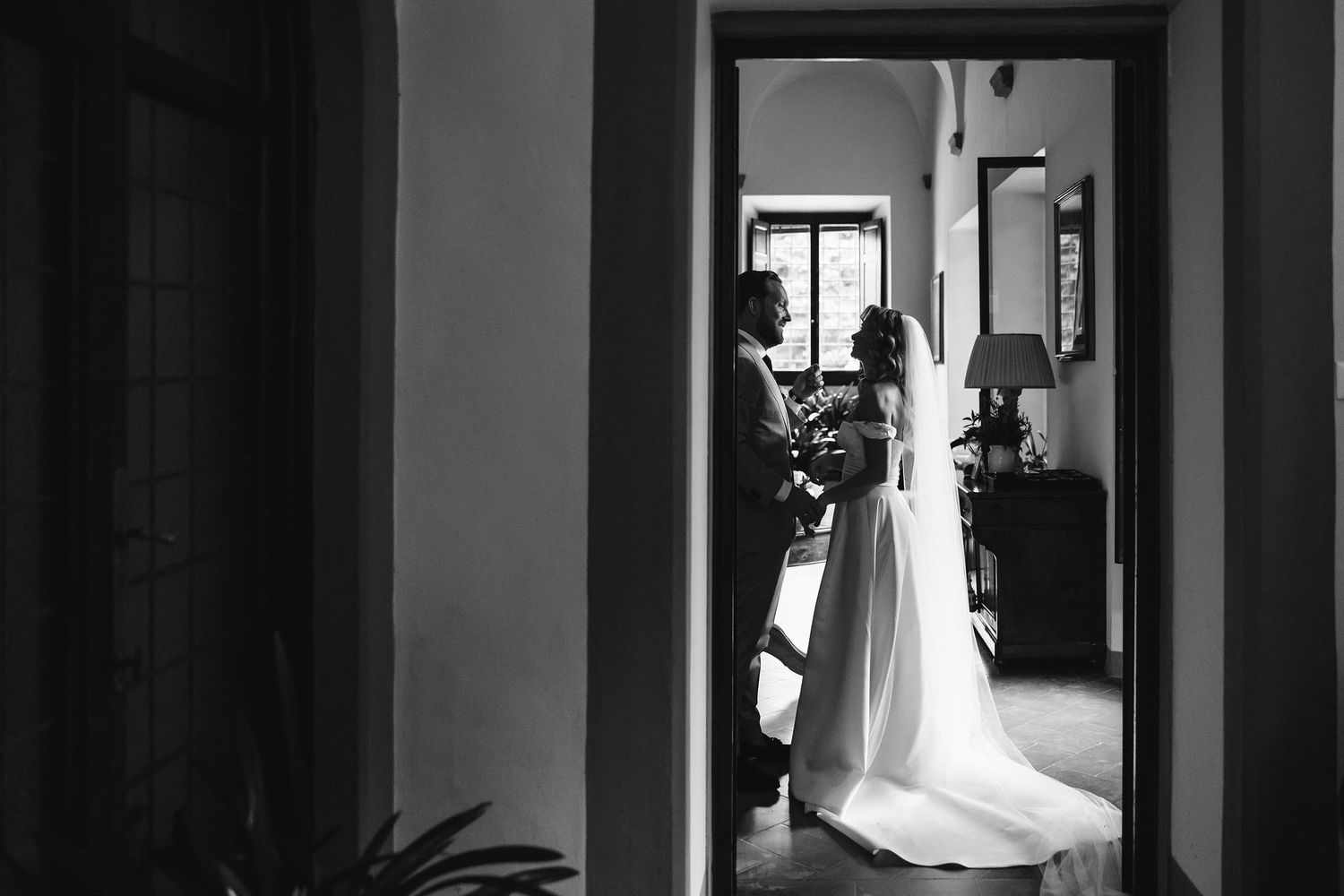 Artistic black and white silhouette of a bride in a doorway.