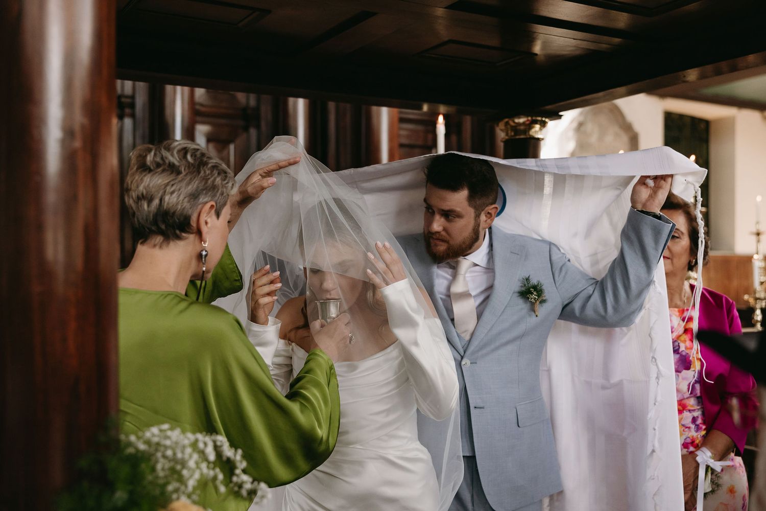 Wedding celebration moment captured with flowing veil and light colored formal attire.