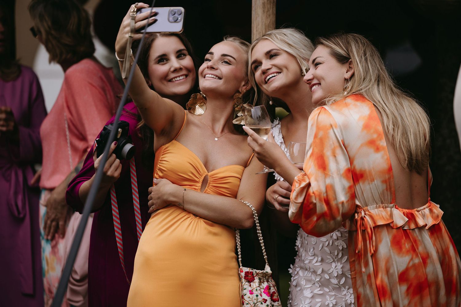 Wedding guests take selfies and share joyful moments at an outdoor celebration.
