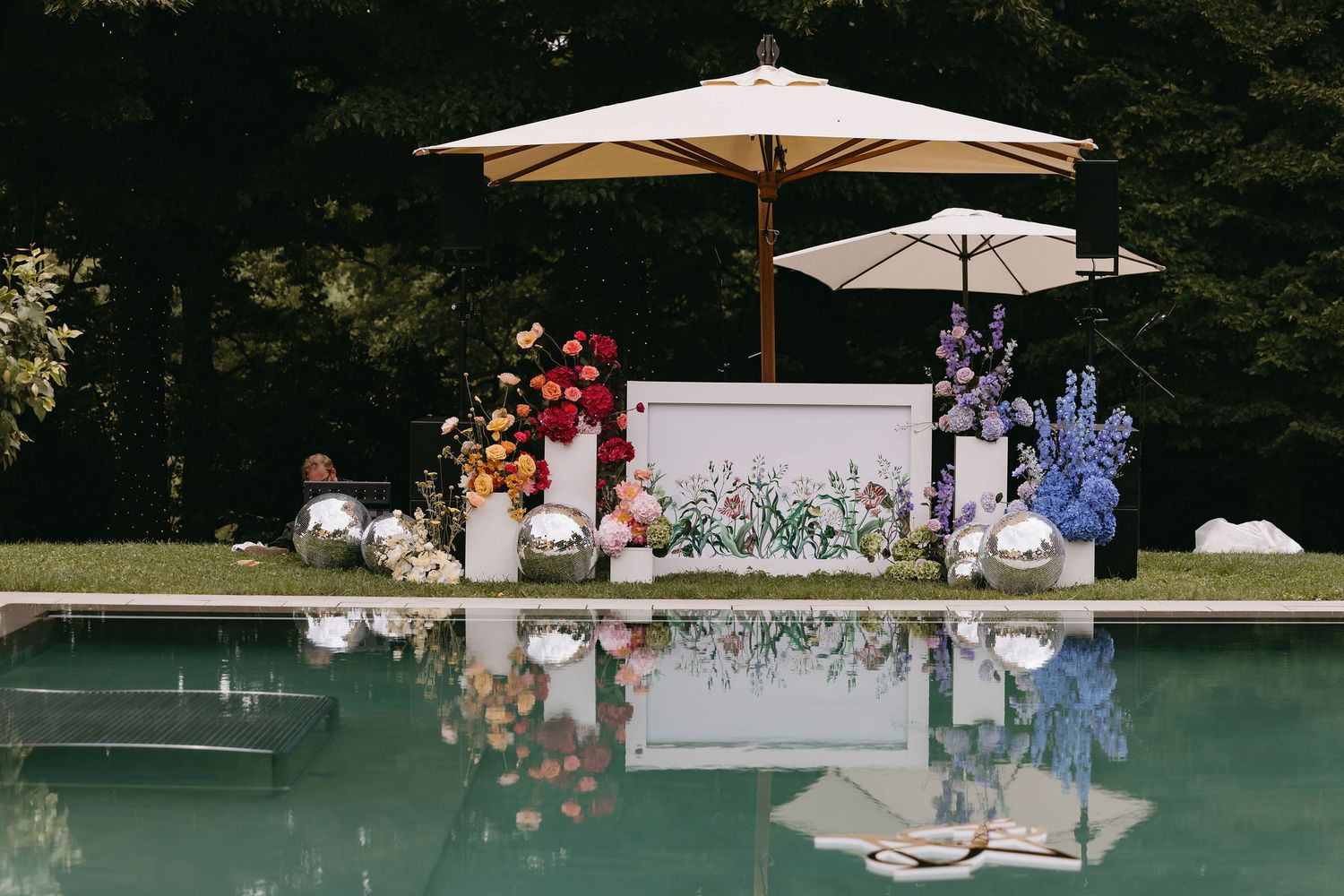 Outdoor wedding reception setup with elegant white umbrellas and tables arranged poolside.