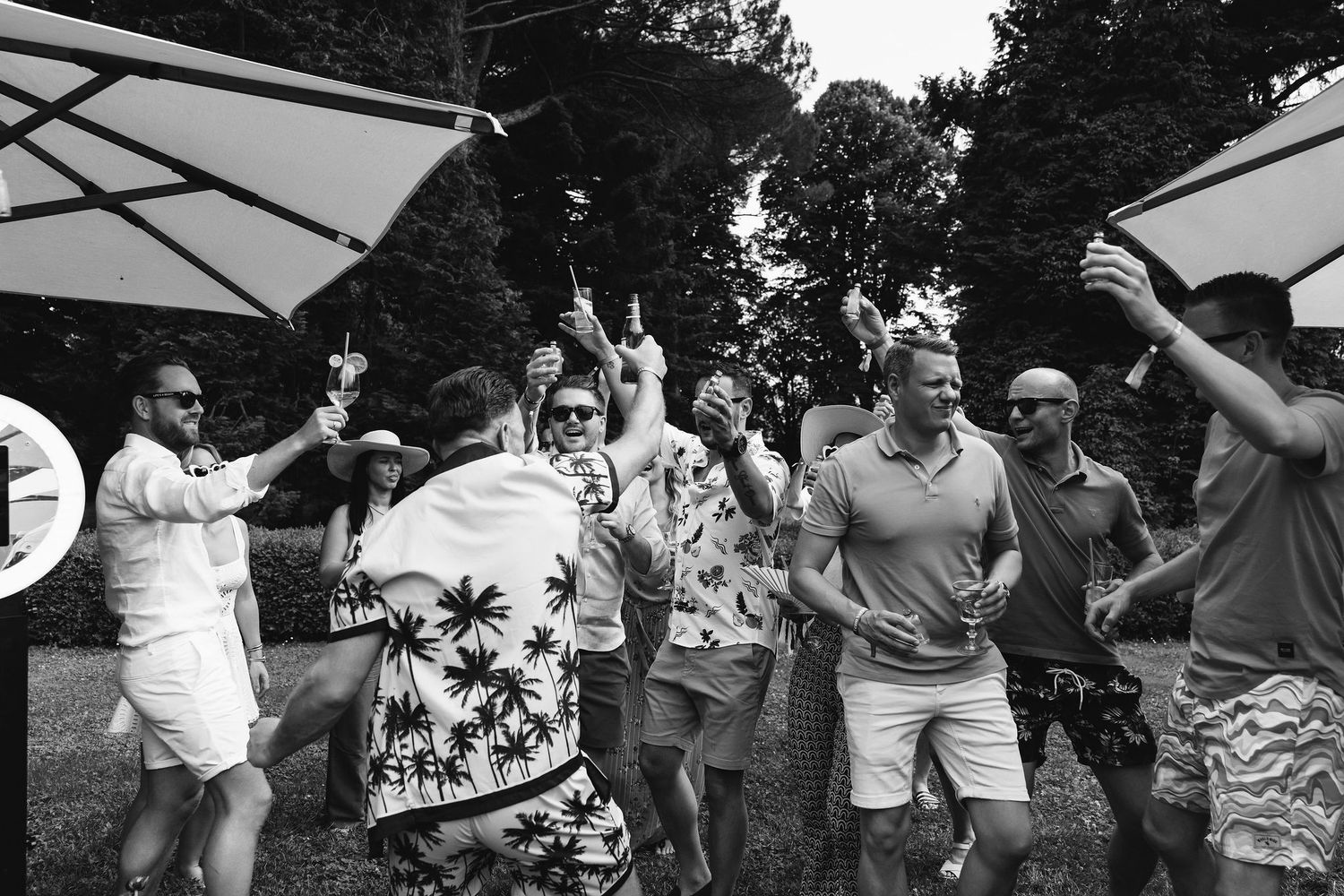 Black and white photo of wedding guests celebrating and dancing outdoors.
