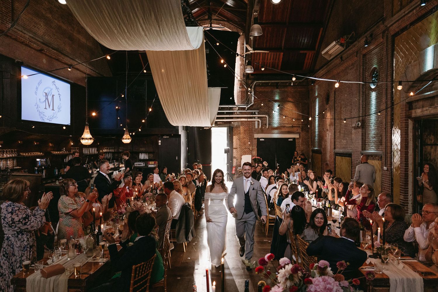 Large indoor reception space with exposed brick walls and hanging lights.