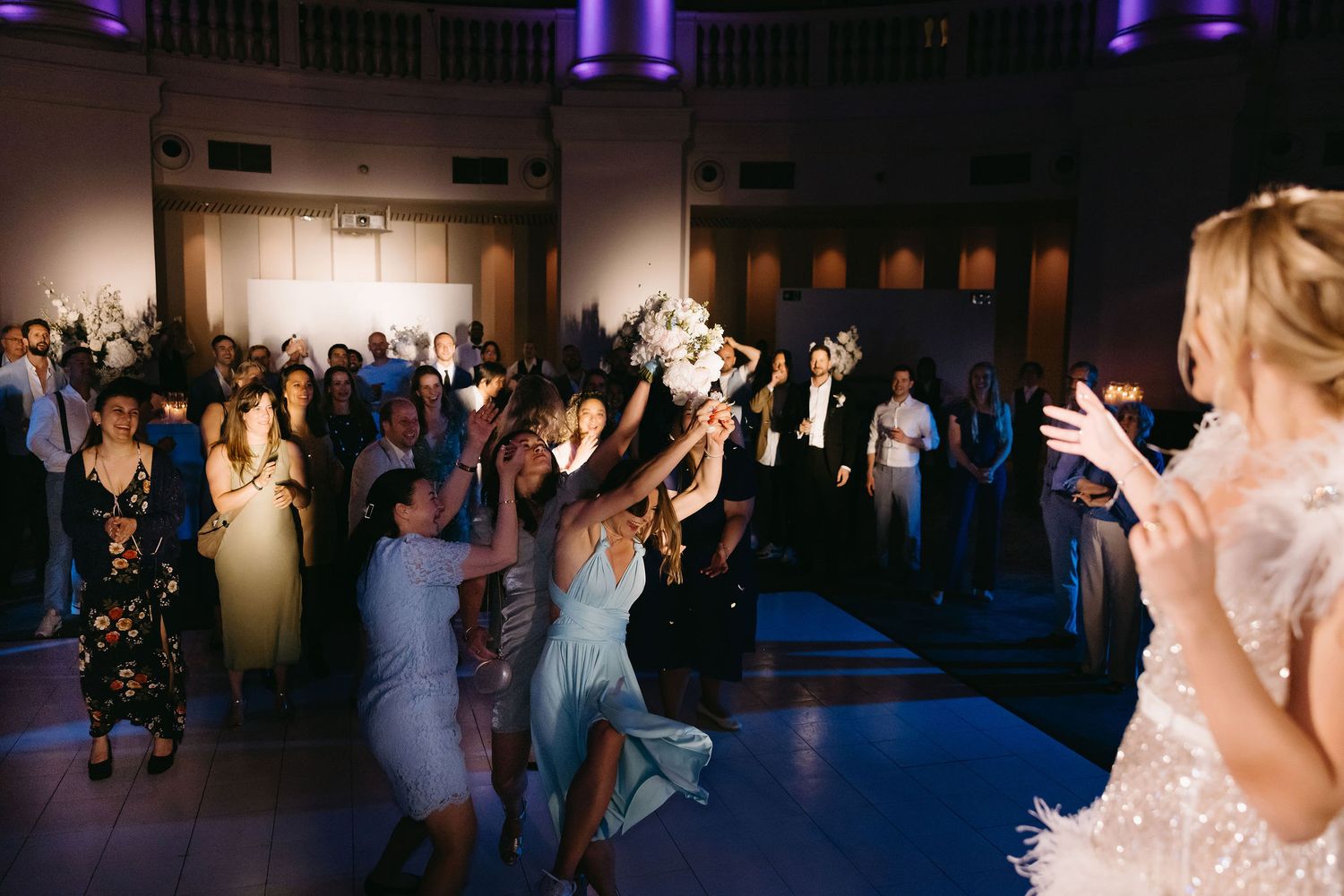 Wedding celebration at night with purple uplighting illuminating the dance floor.