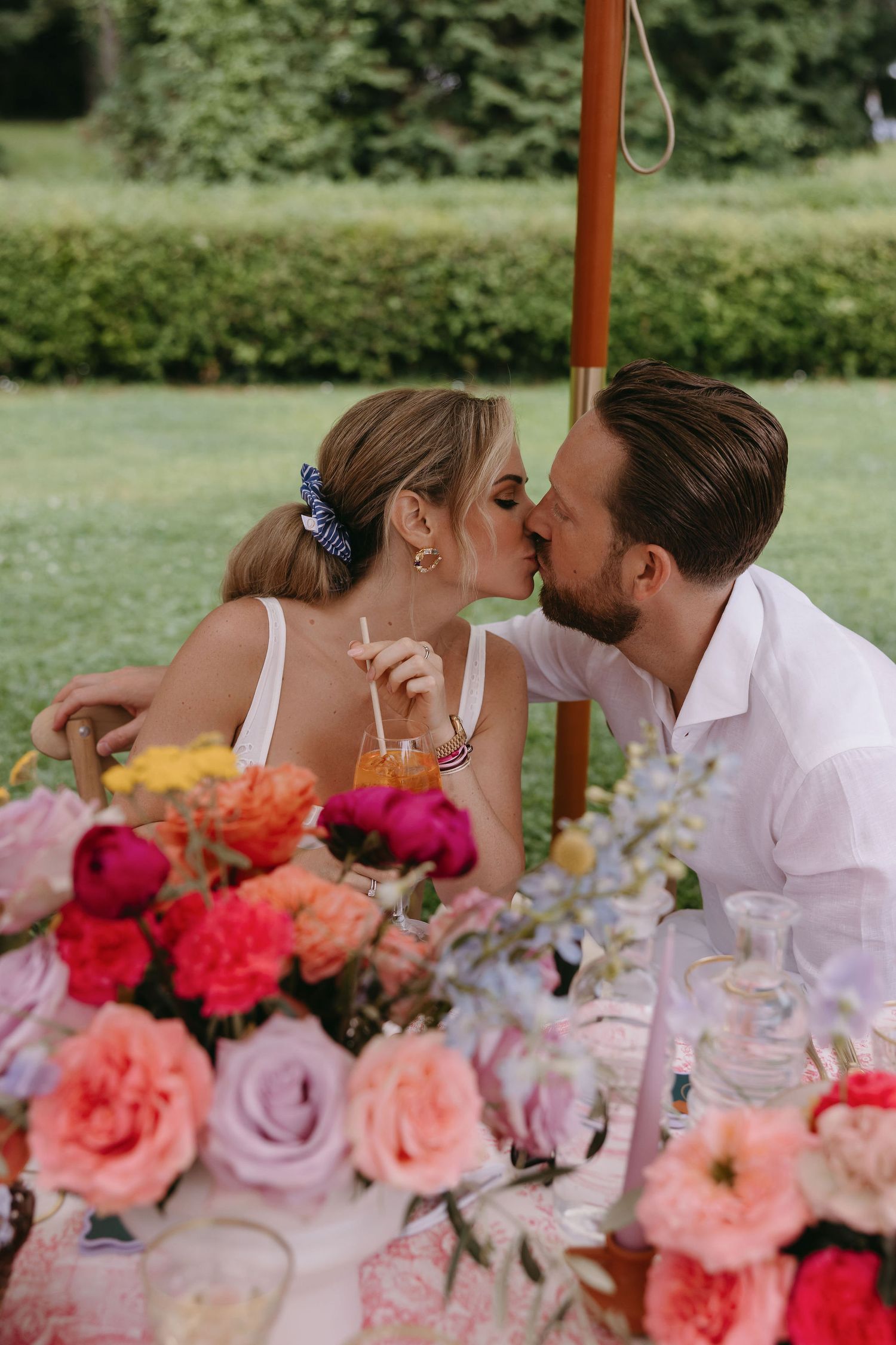 Romantic table setting adorned with colorful roses and glassware for an outdoor celebration.