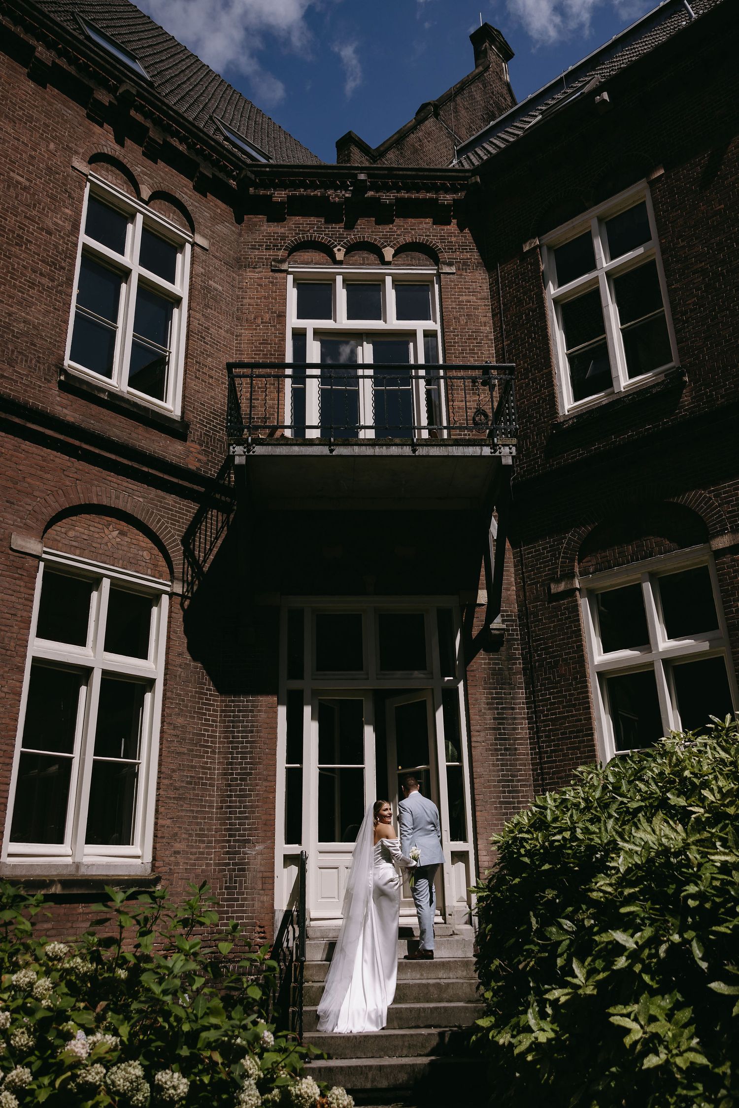 A panoramic view of a historic brick building with white windows and overhanging balconies against a blue sky.